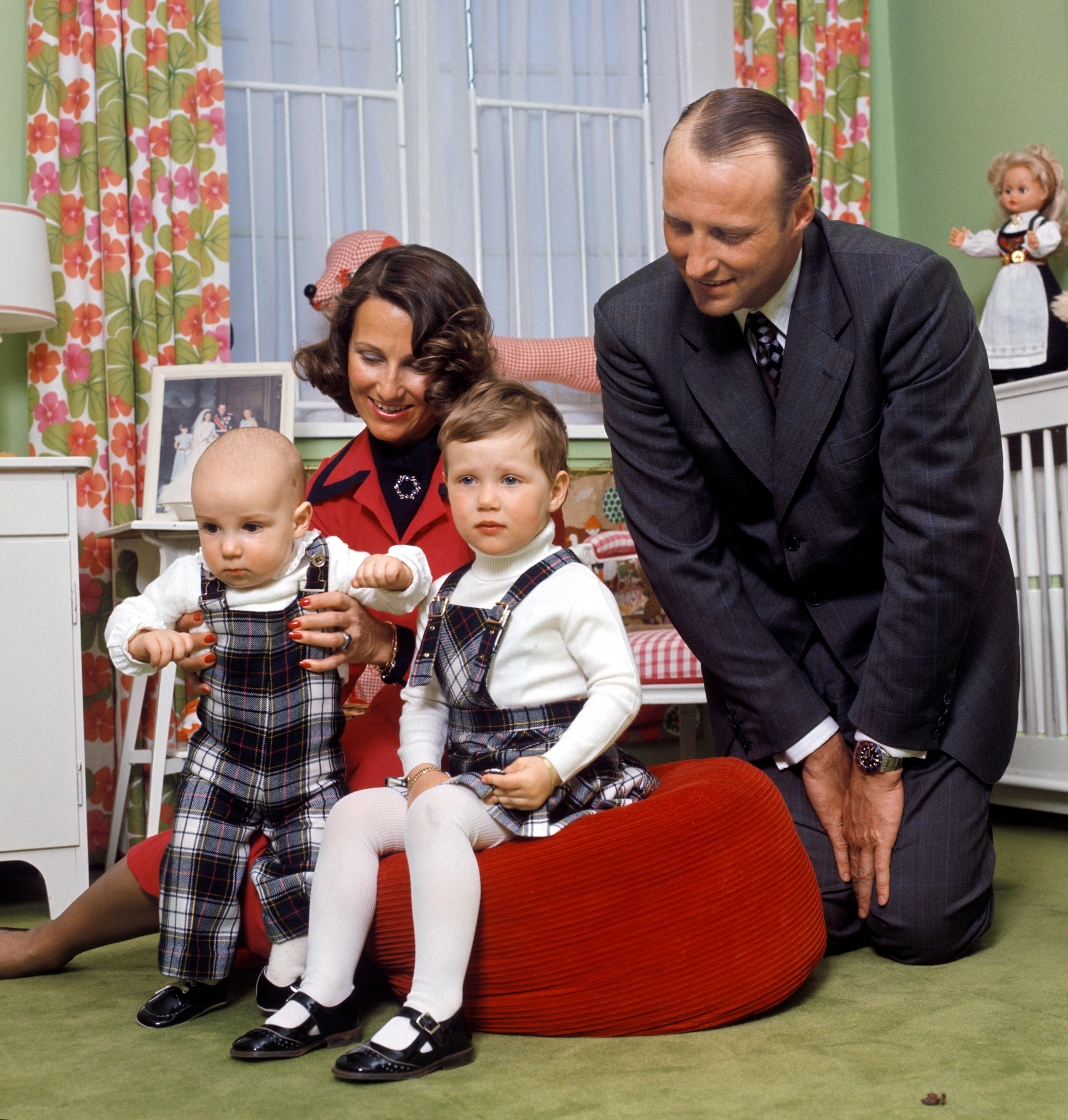 Kronprins Harald og Kronprinsesse Sonja sitter med barna foran seg. Prins Haakon Magnus er 8 måneder og holdes oppe av mamma.