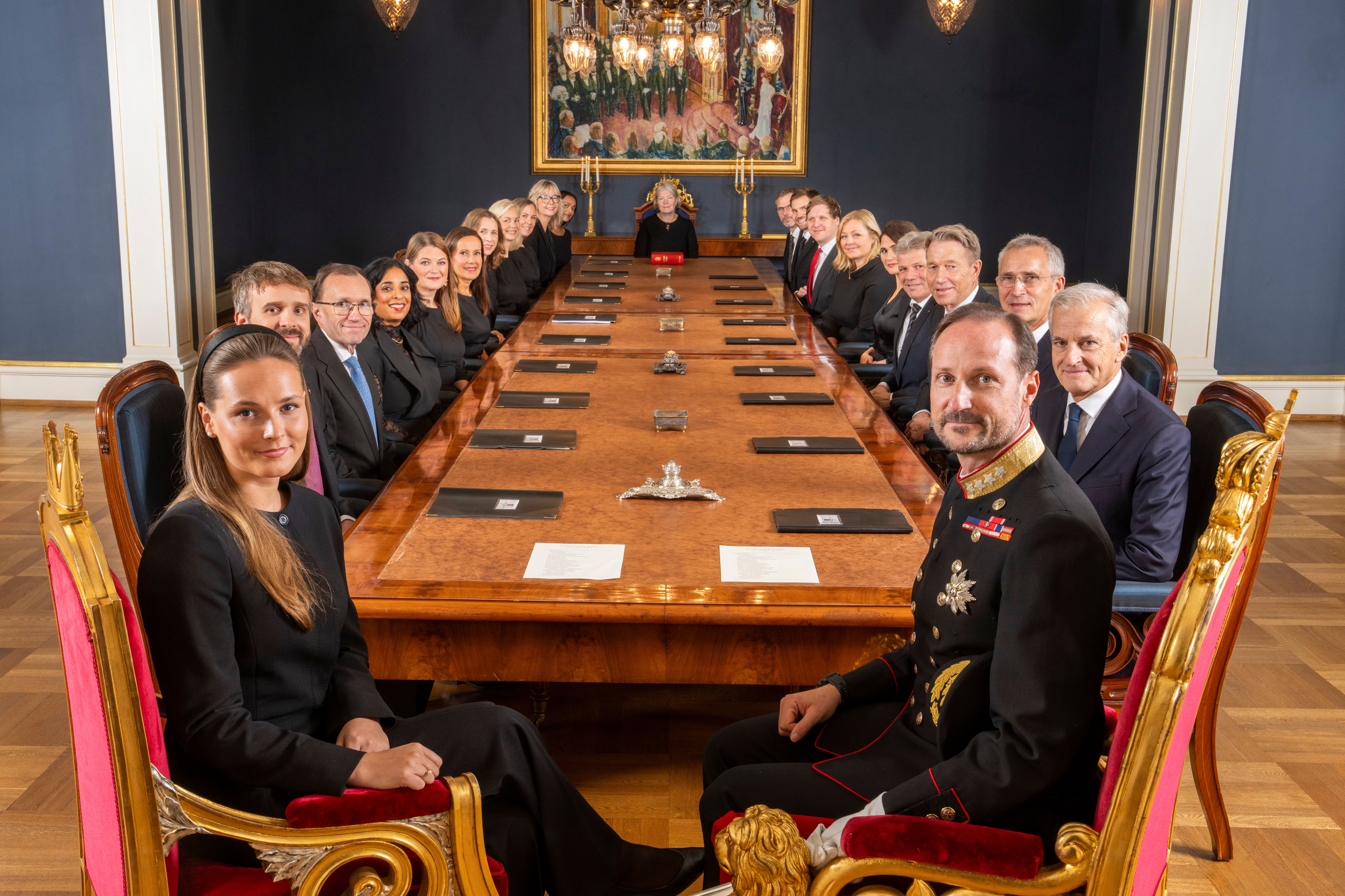 Oversiktsbilde fra Statsrådsalen. Kongen og Kronprinsessen sitter nærmest kameraet, og regjeringens medlemmer nedover på begge sider av det lange bordet.