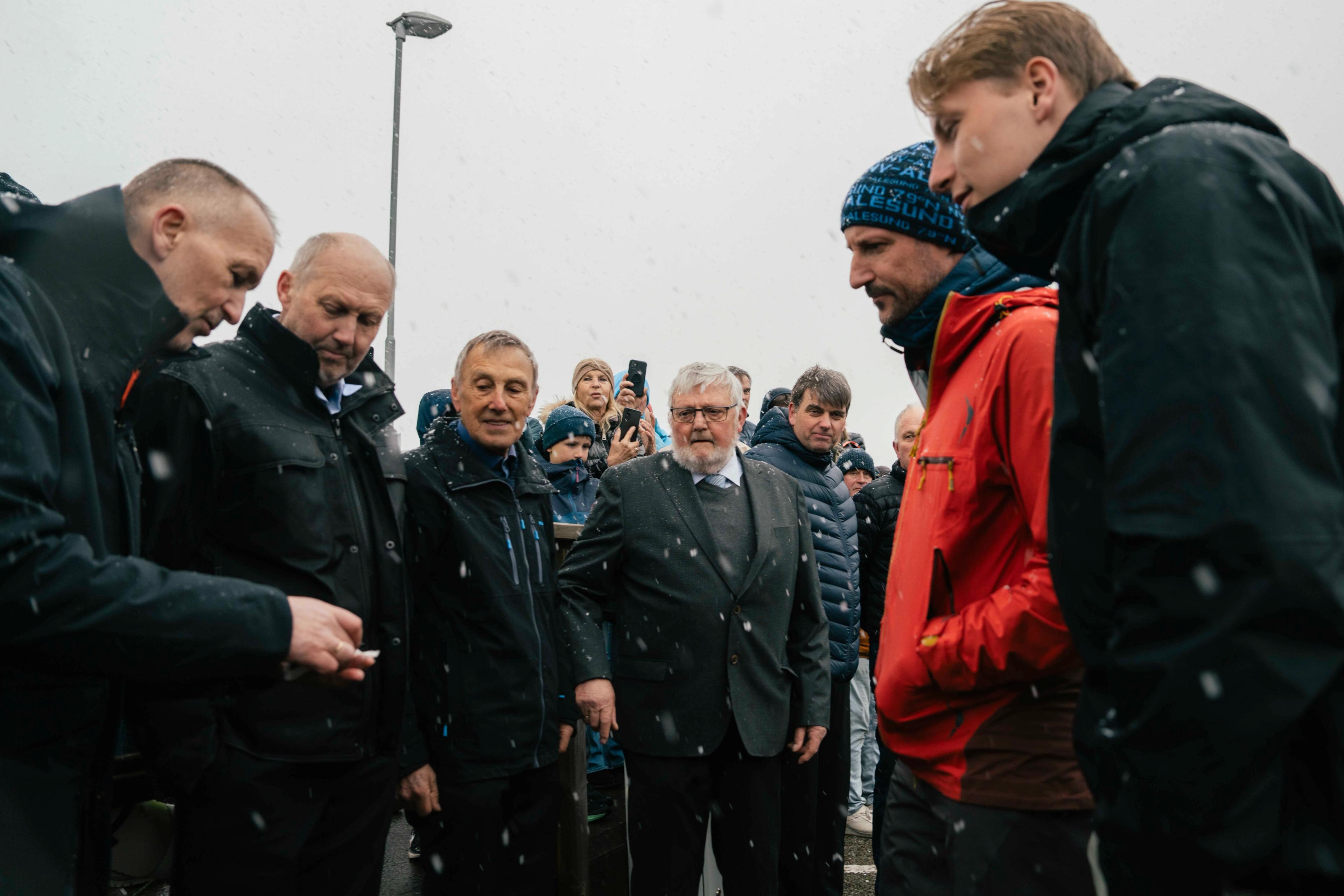Kronprins Haakon og Prins Sverre Magnus møter båtbyggerne av Myklebustskipet på brygga i snøvær
