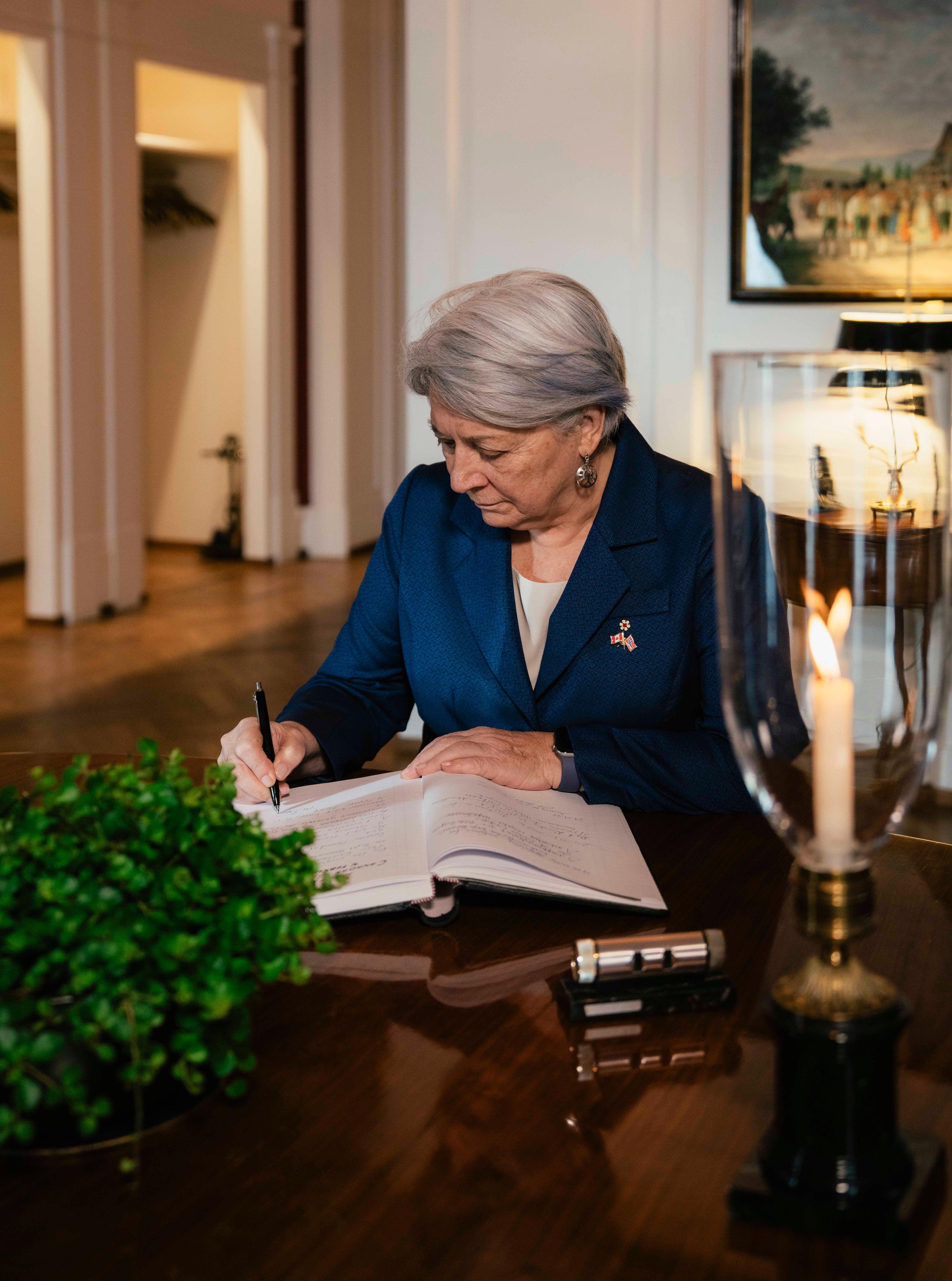 Mary Simon sitter ved et skrivebord og signerer sin hilsen.