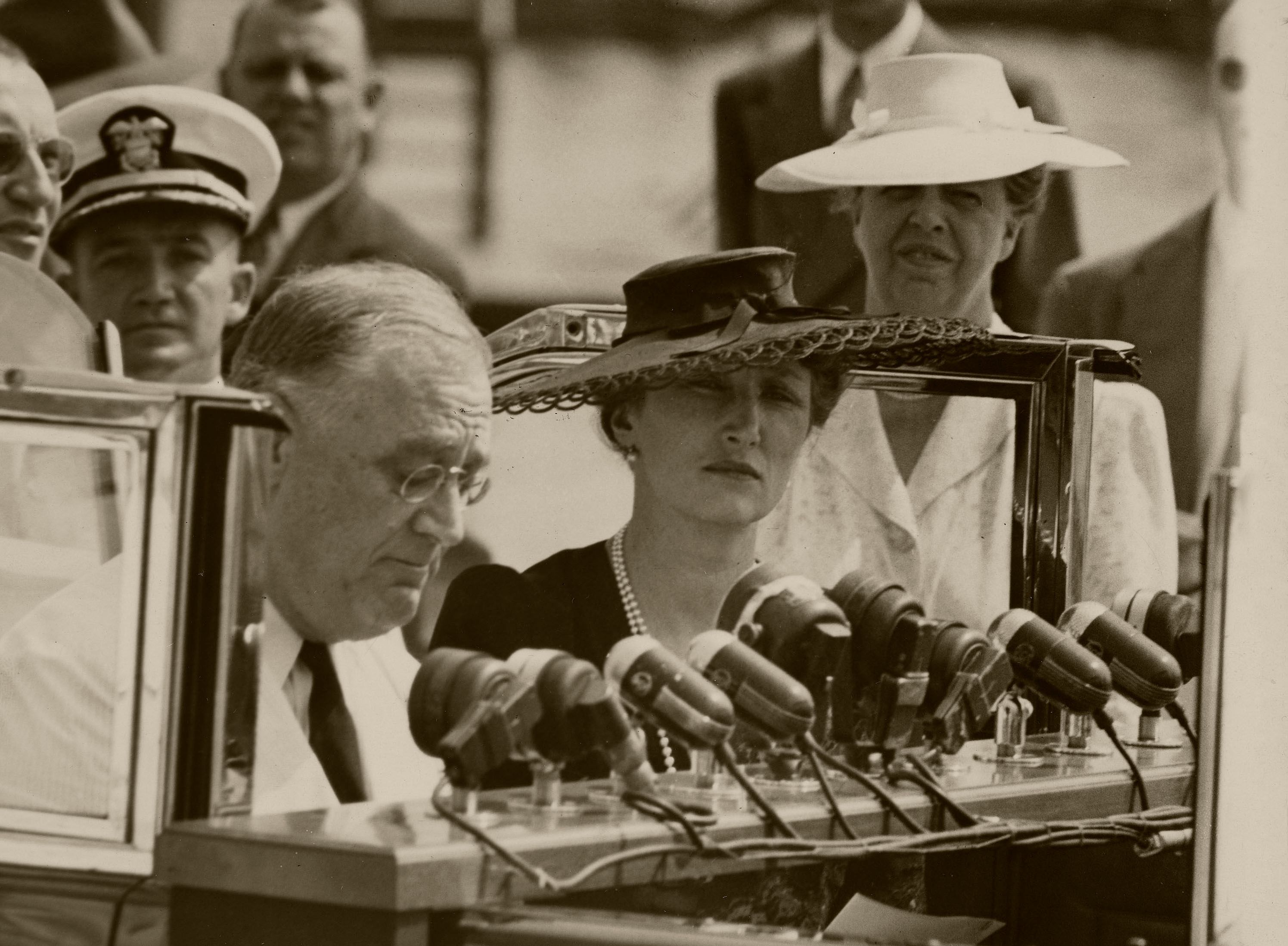 President Roosevelt foran en lang rekke mikrofoner. Kronprinsesse Mæartha står ved siden av ham.