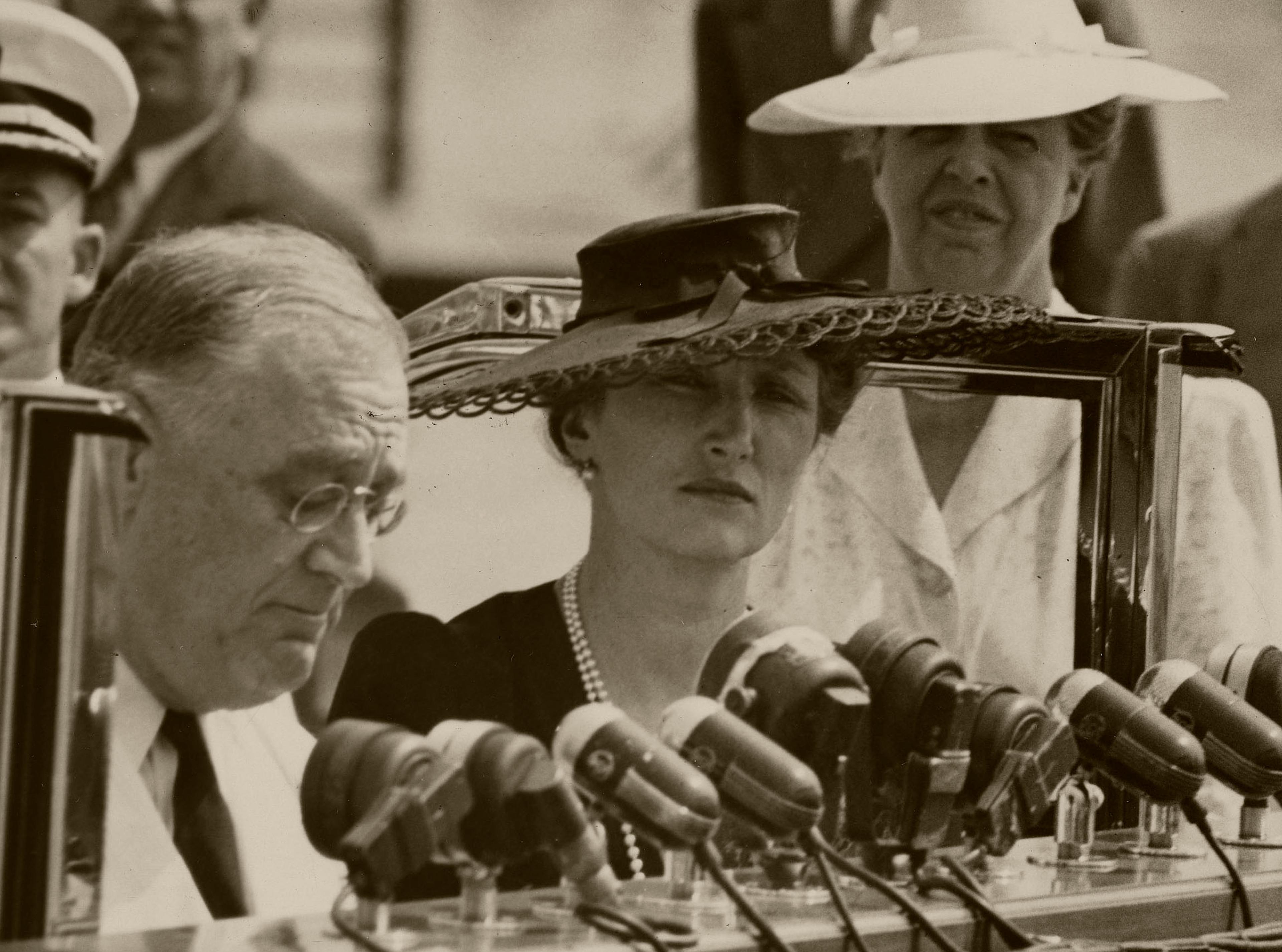 President Roosevelt foran en lang rekke mikrofoner. Kronprinsesse Mæartha står ved siden av ham.