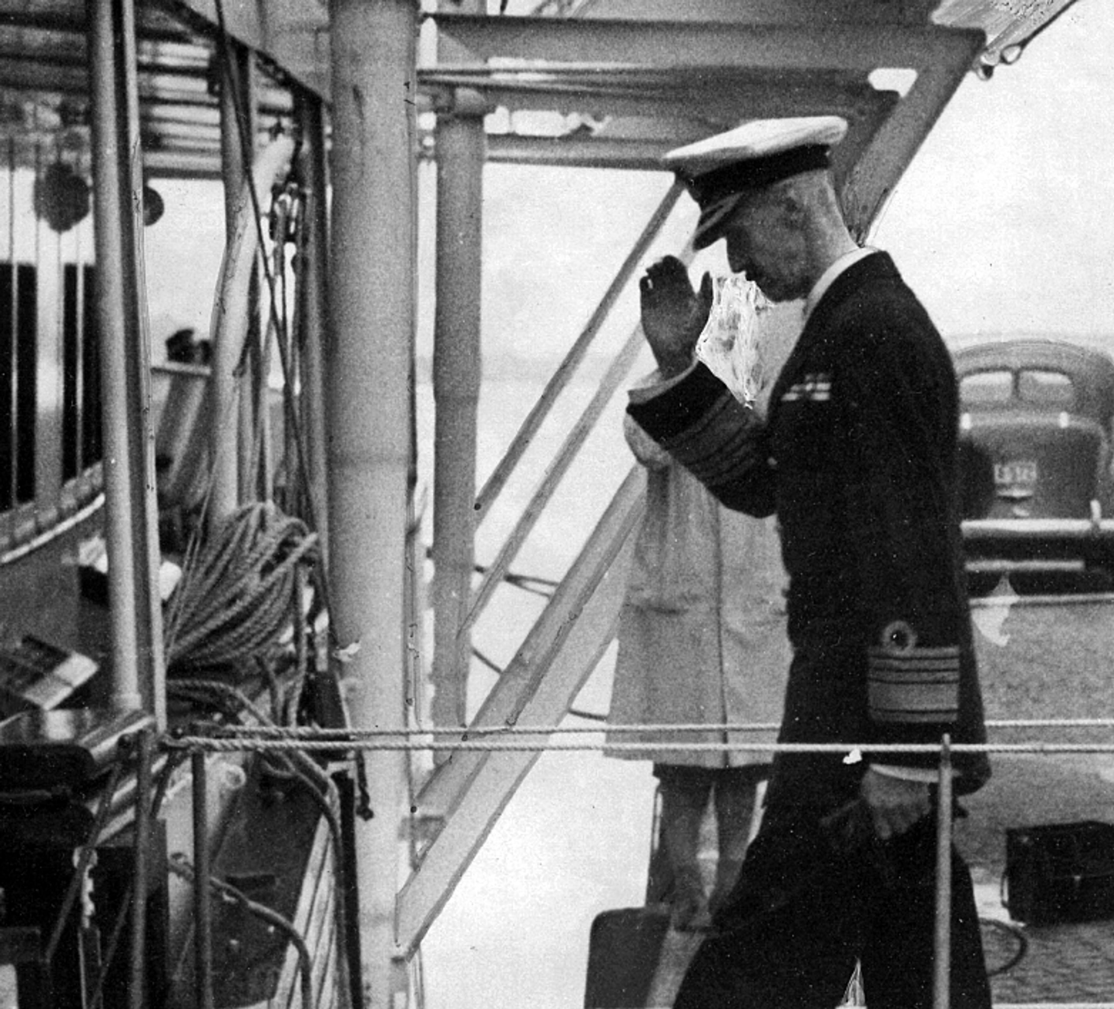 Kong Haakon går opp gangveien fra kaia til Kongeskipet. Han gjør honnør idet han går om bord.