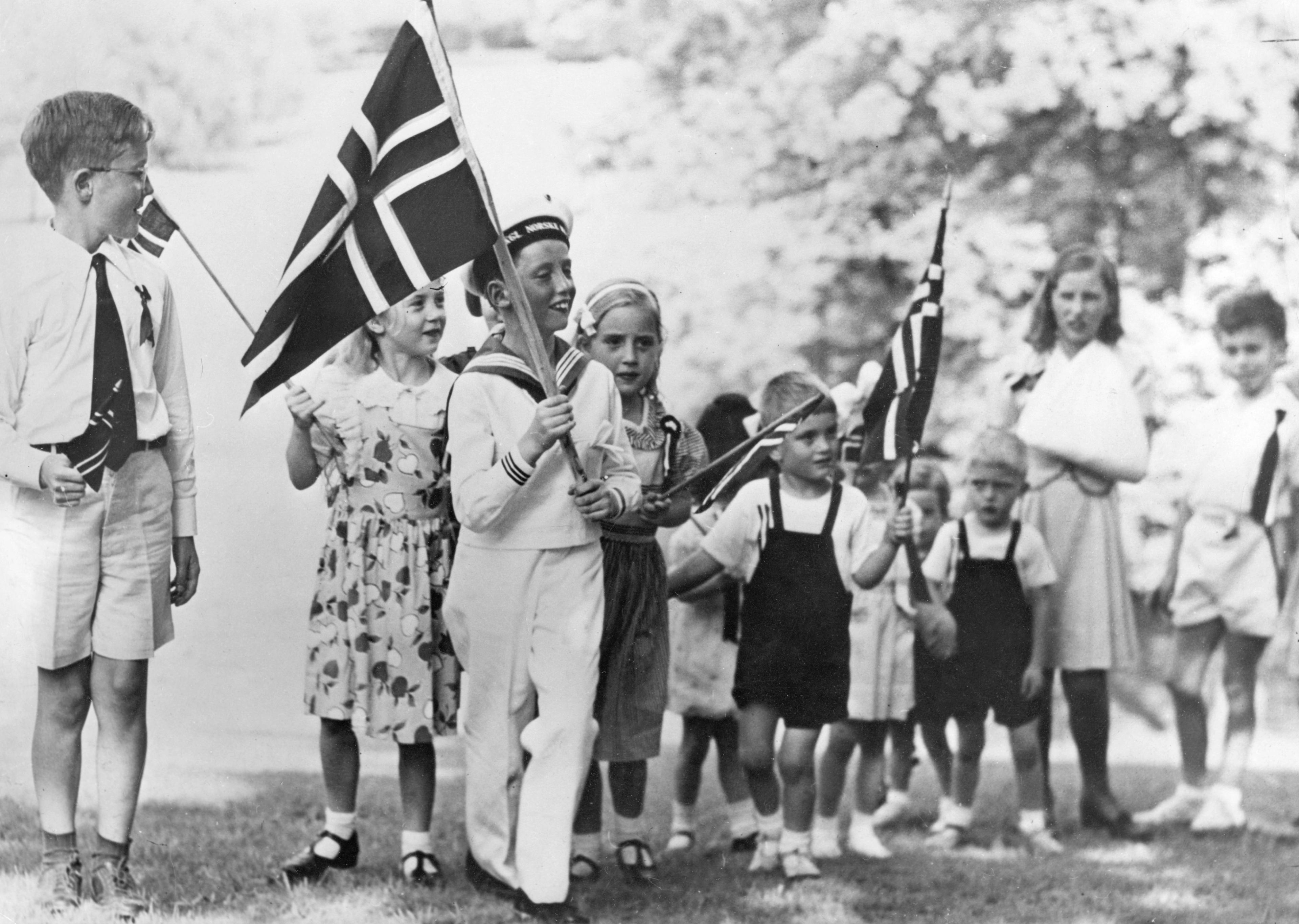 Prins Haralds bærer et stort, norsk flagg foran i barnetoget.