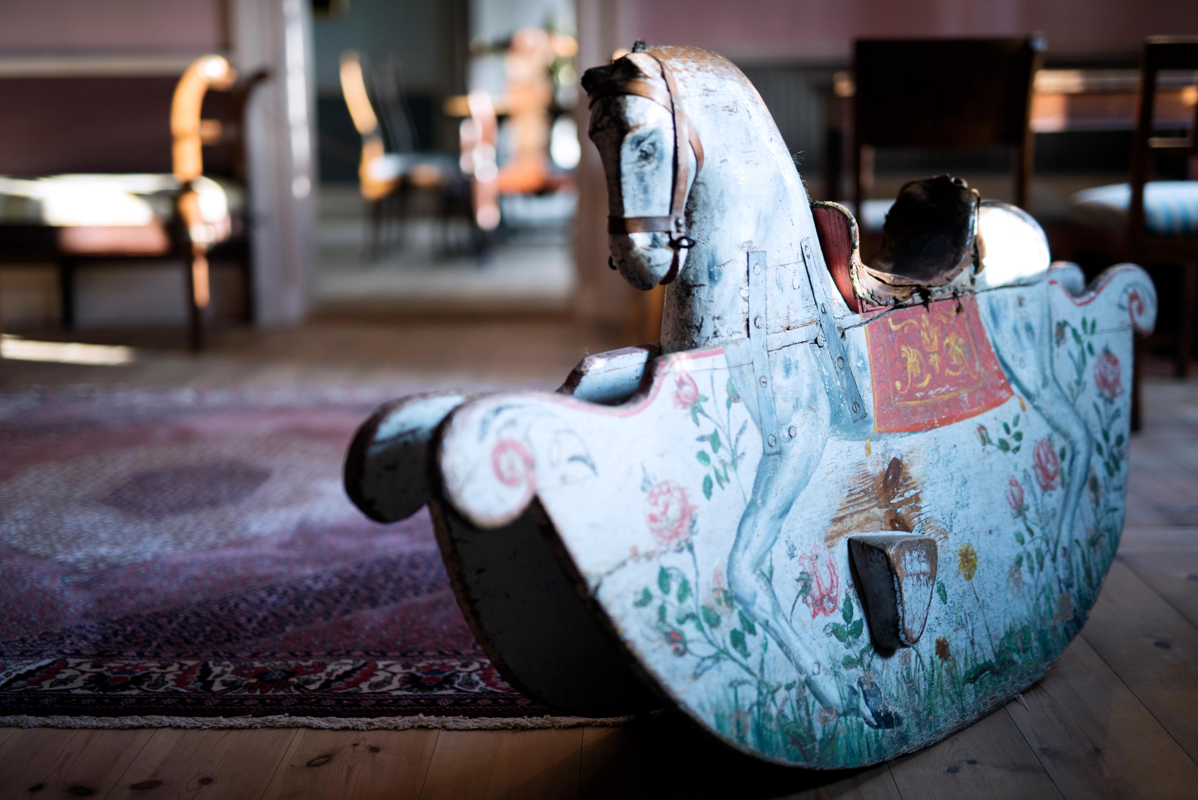 Nærbilde av en gammel gyngehest i tre med falmet maling.