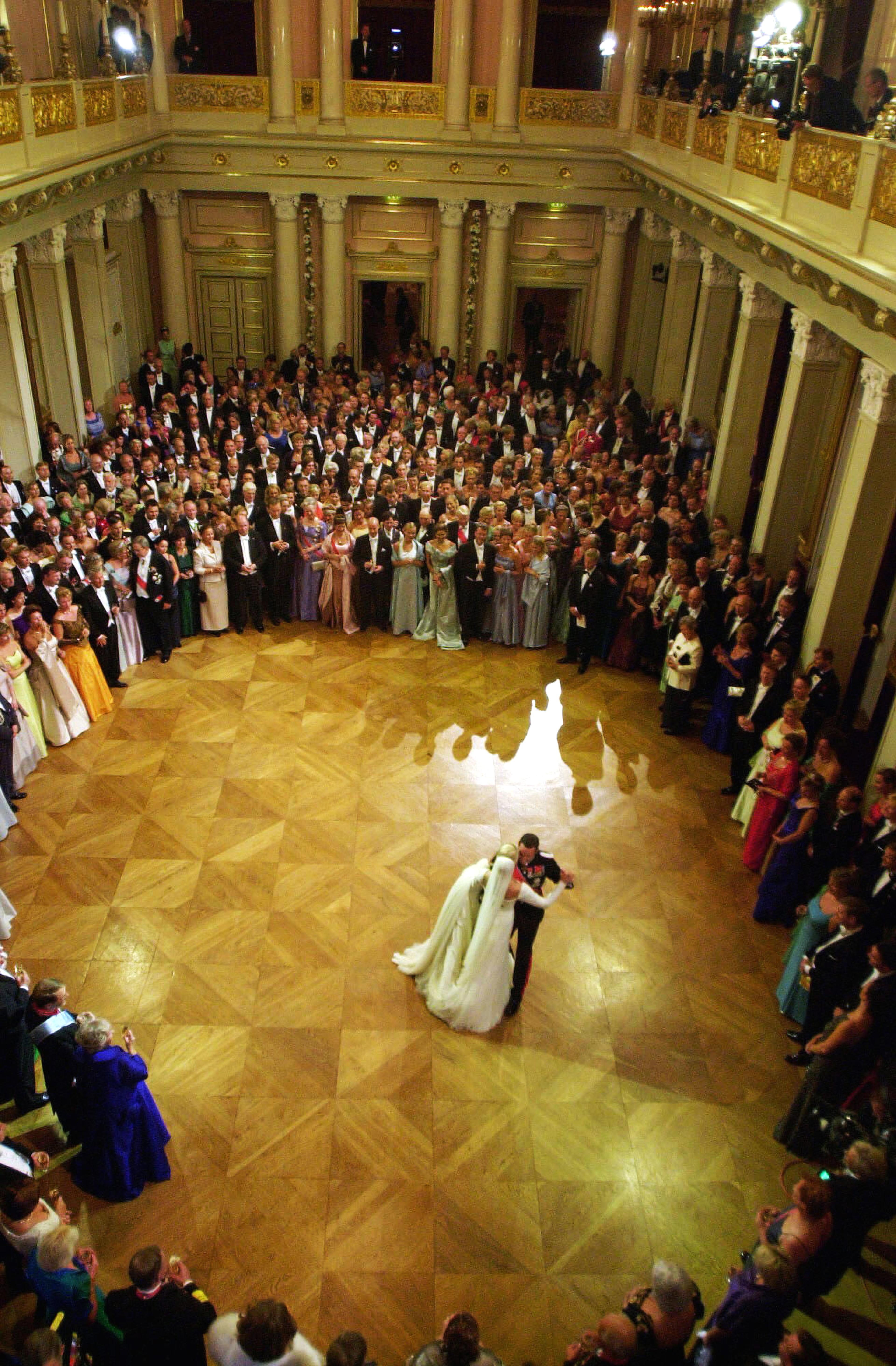 Kronprinsparet danser alene. Festkledde bryllupsgjster står i en vid sirkel omkring dem.