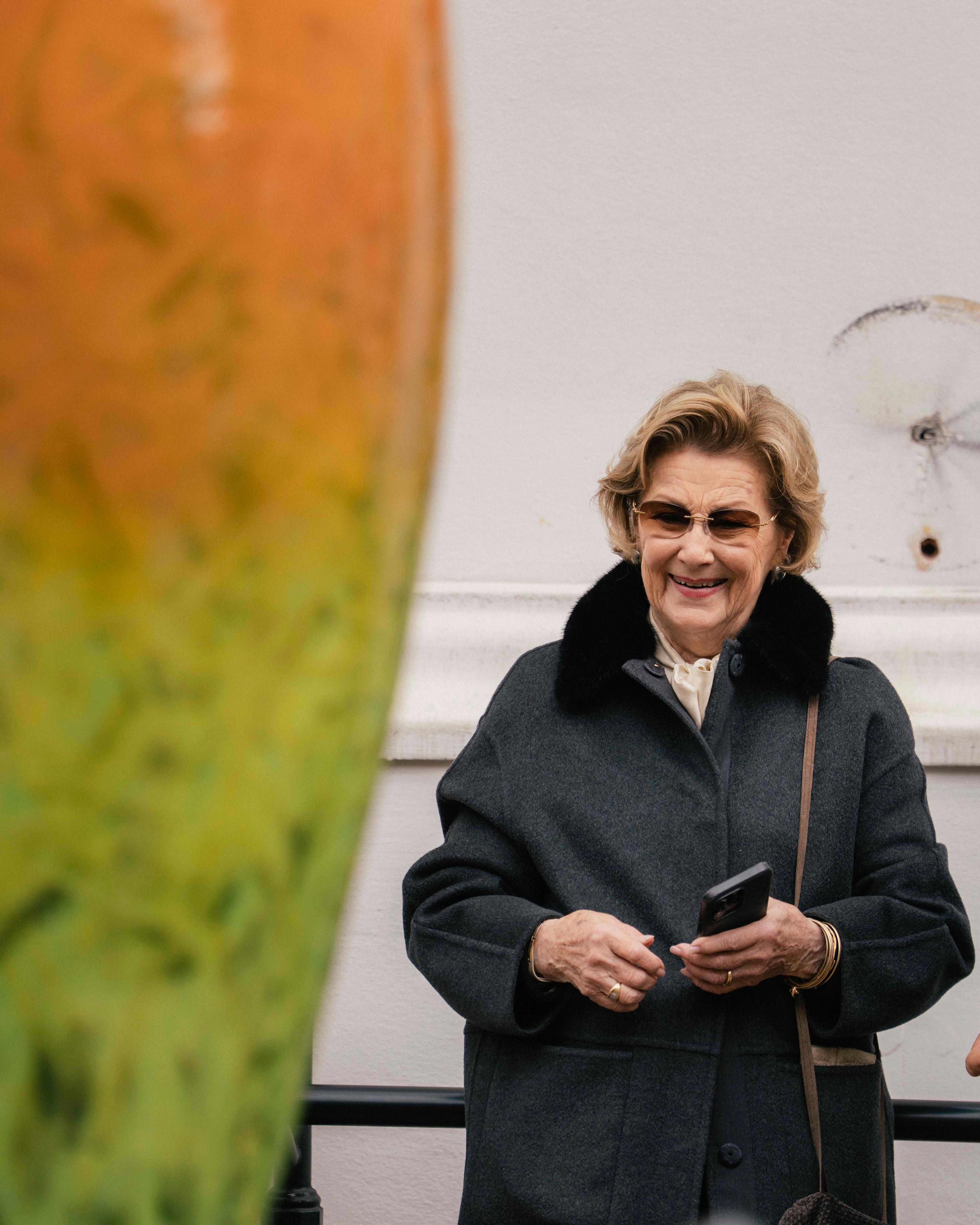 Dronning Sonja ser smilende på en av krukkene, som ses i utsnitt nærmest i bildet.