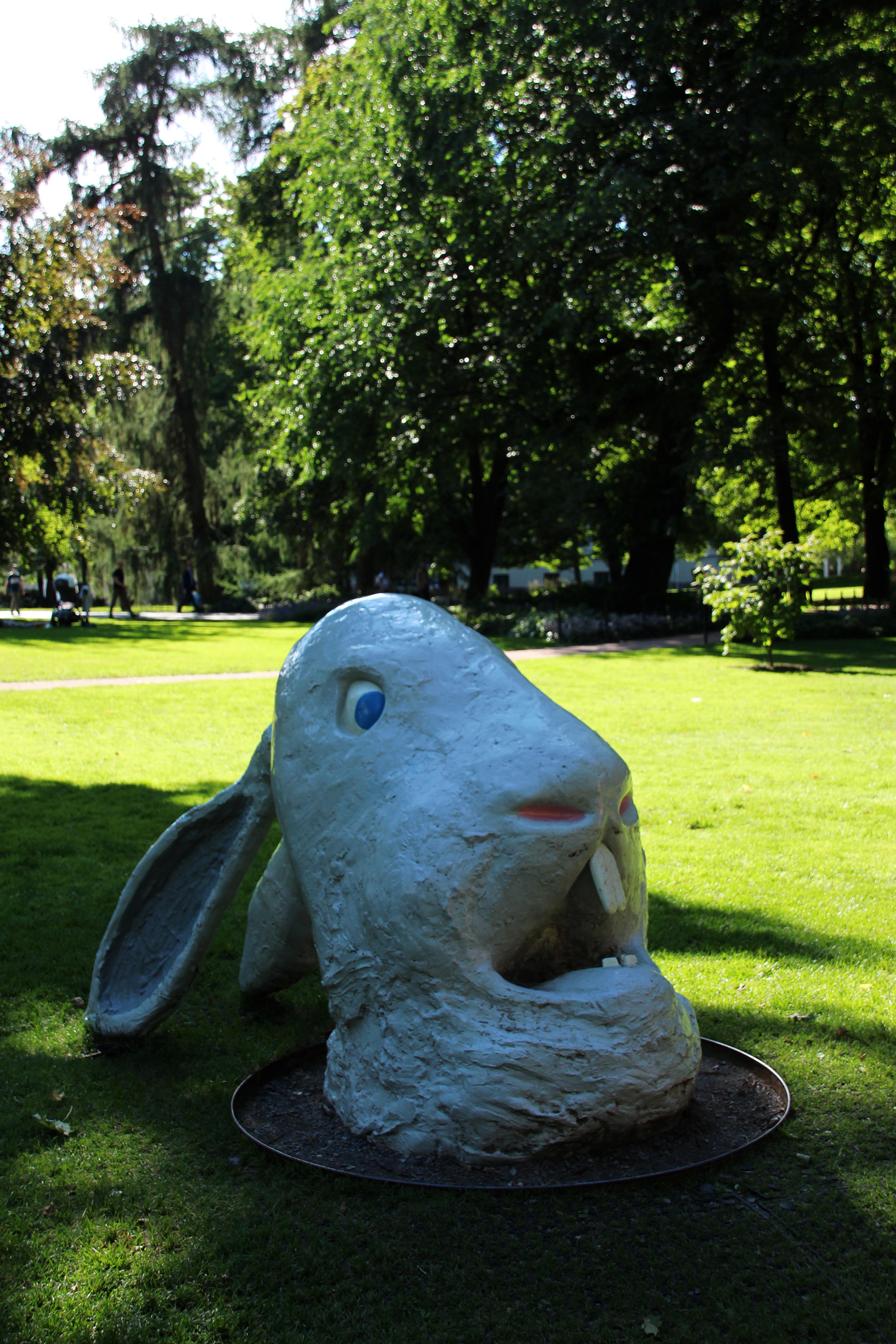 Et stort, støpt kaninhode med ørene bakover, åpen munn med store tenner, blå øyne og et forskrekket uttrykk.
