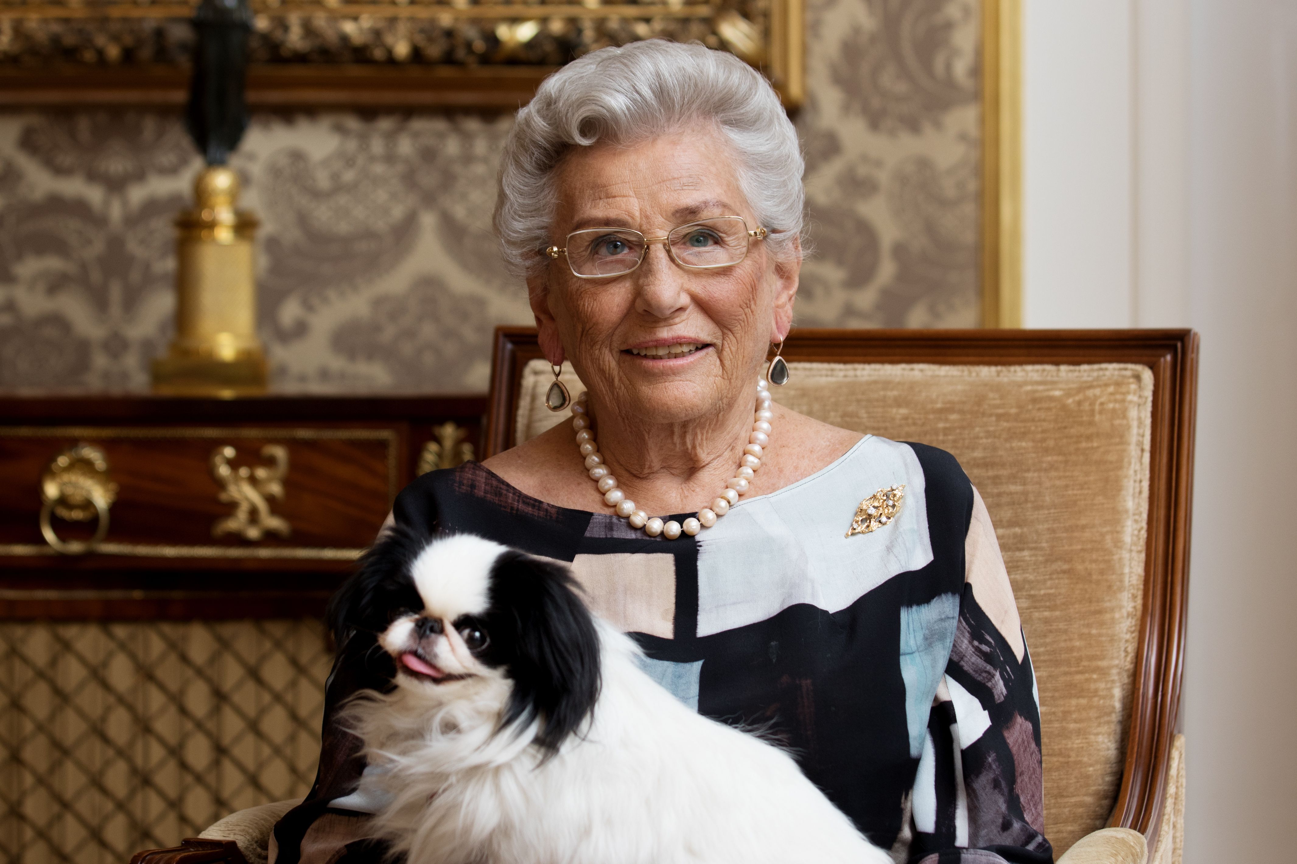 Portrett av Prinsesse Astrid sittende i stol sammen med hunden sin Tarzan.