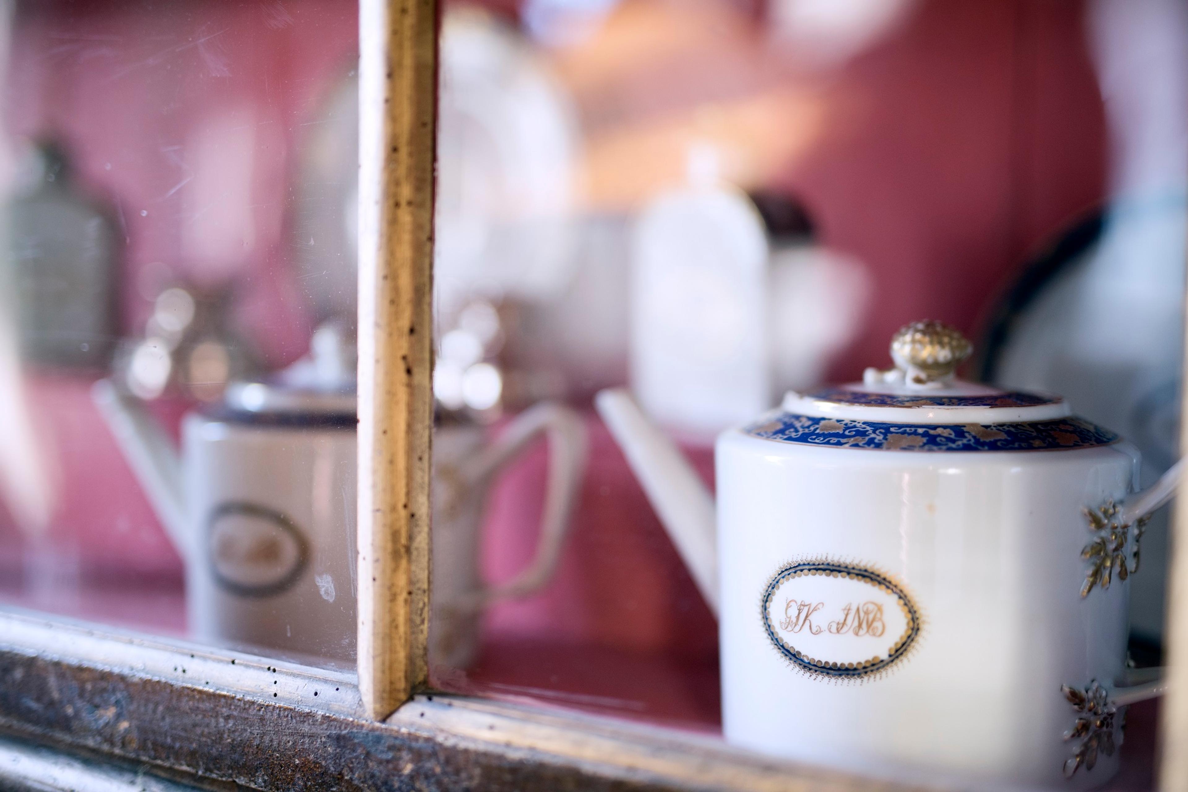 En gammel tekanne - hvit med monogram og dekor i blått og gull.