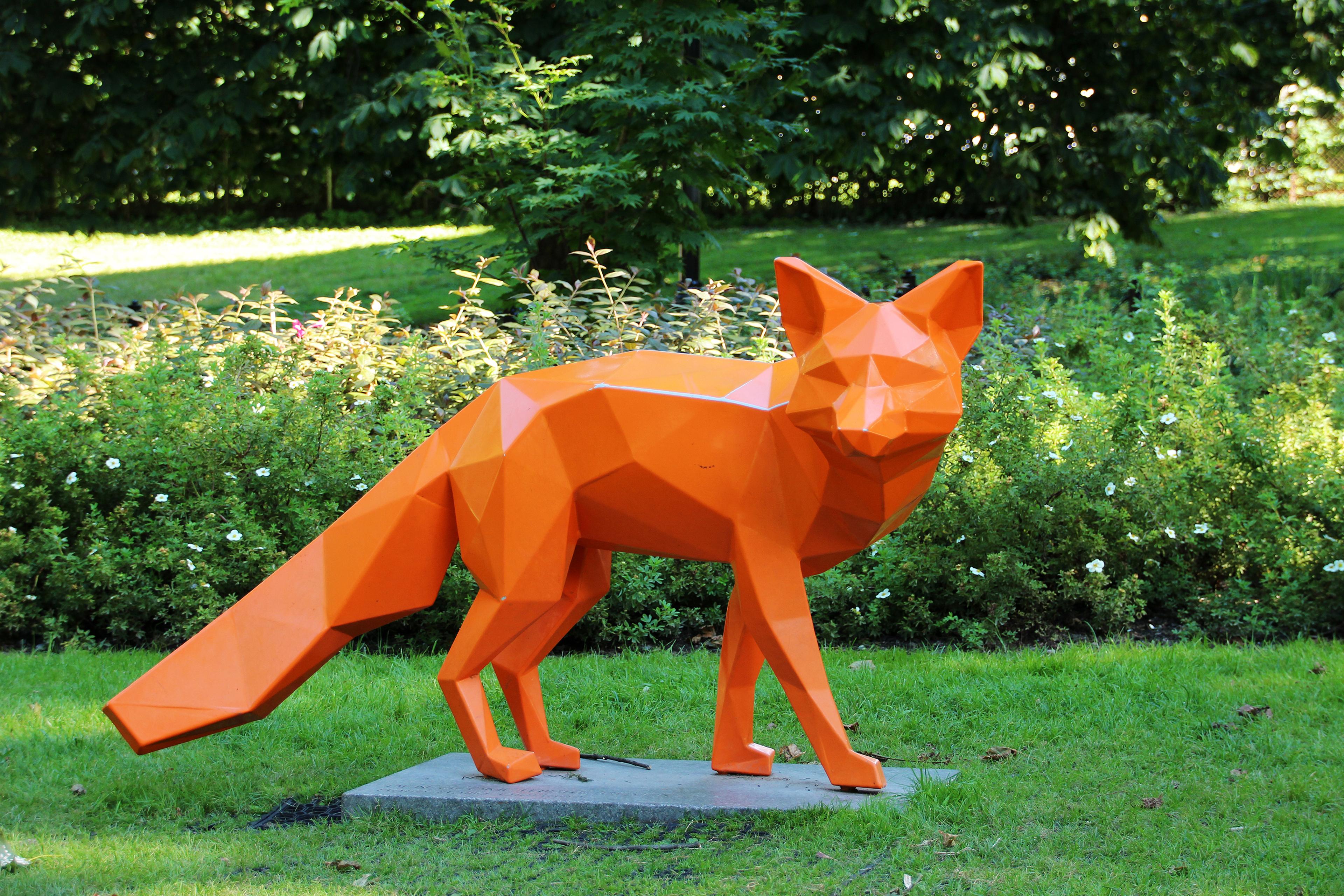 En rev i hardt, orange materiale ser seg til høyre. Kroppen er ikke avrundet, men er utformet med kanter, flater og vinkler.