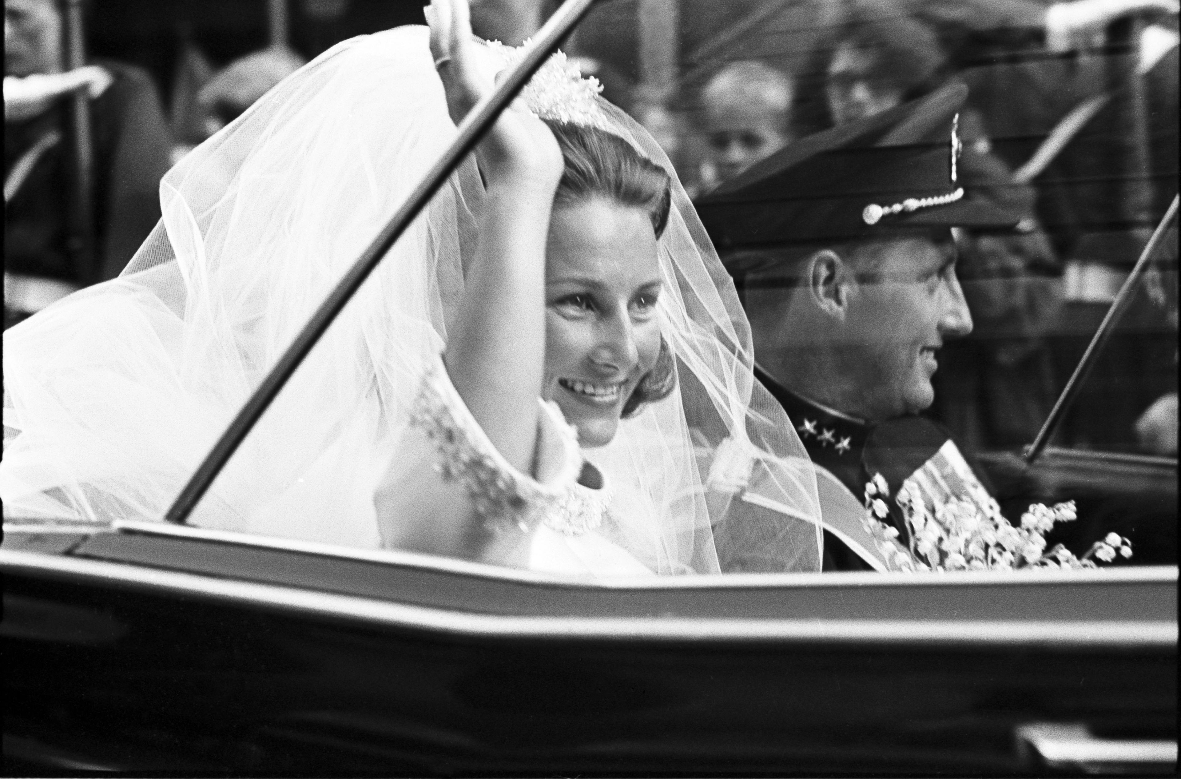 Tett på Dronning Sonja som vinker fra den åpne bilen.
