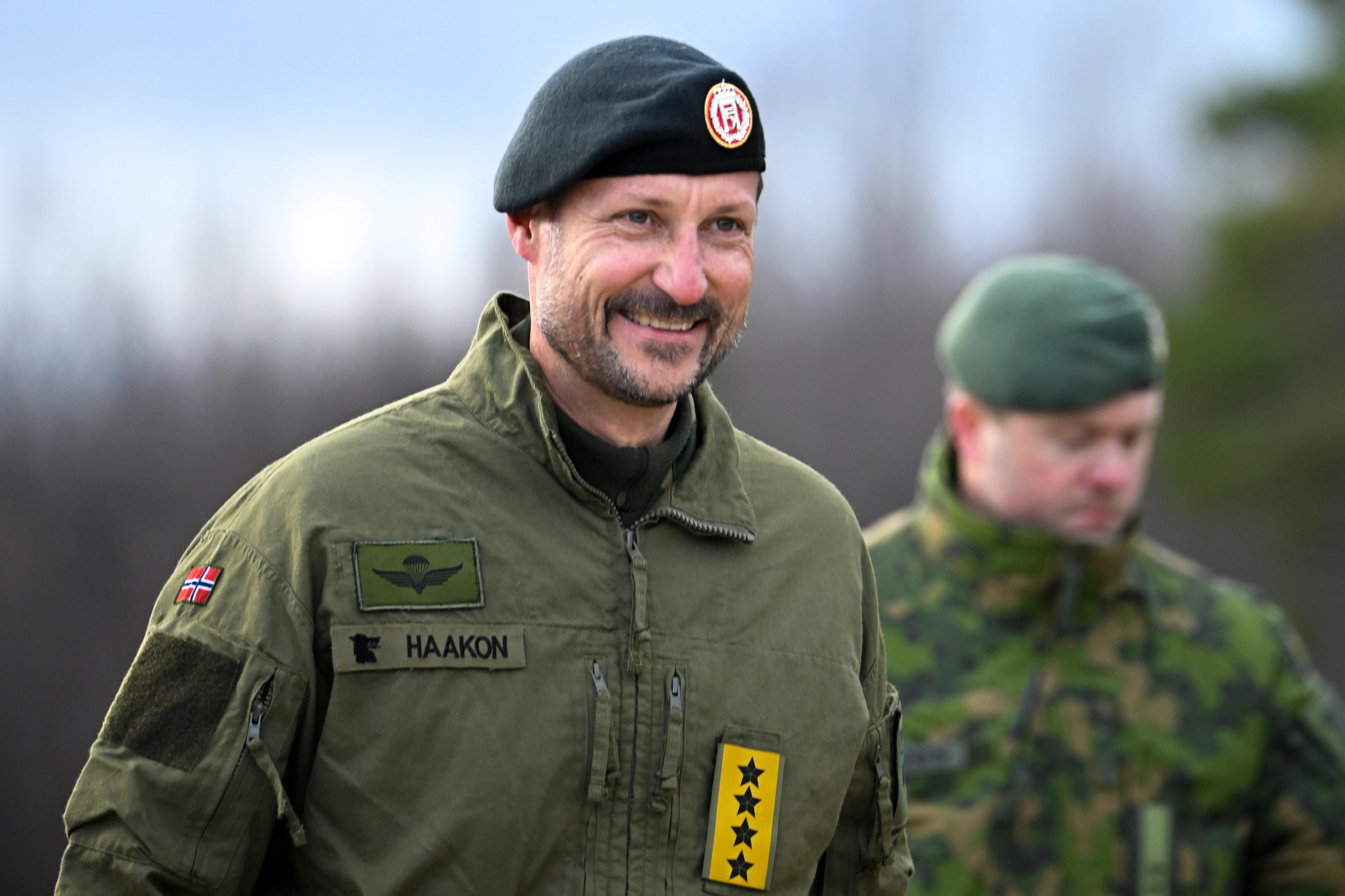 En smilende Kong Haakon i feltutstyr.
