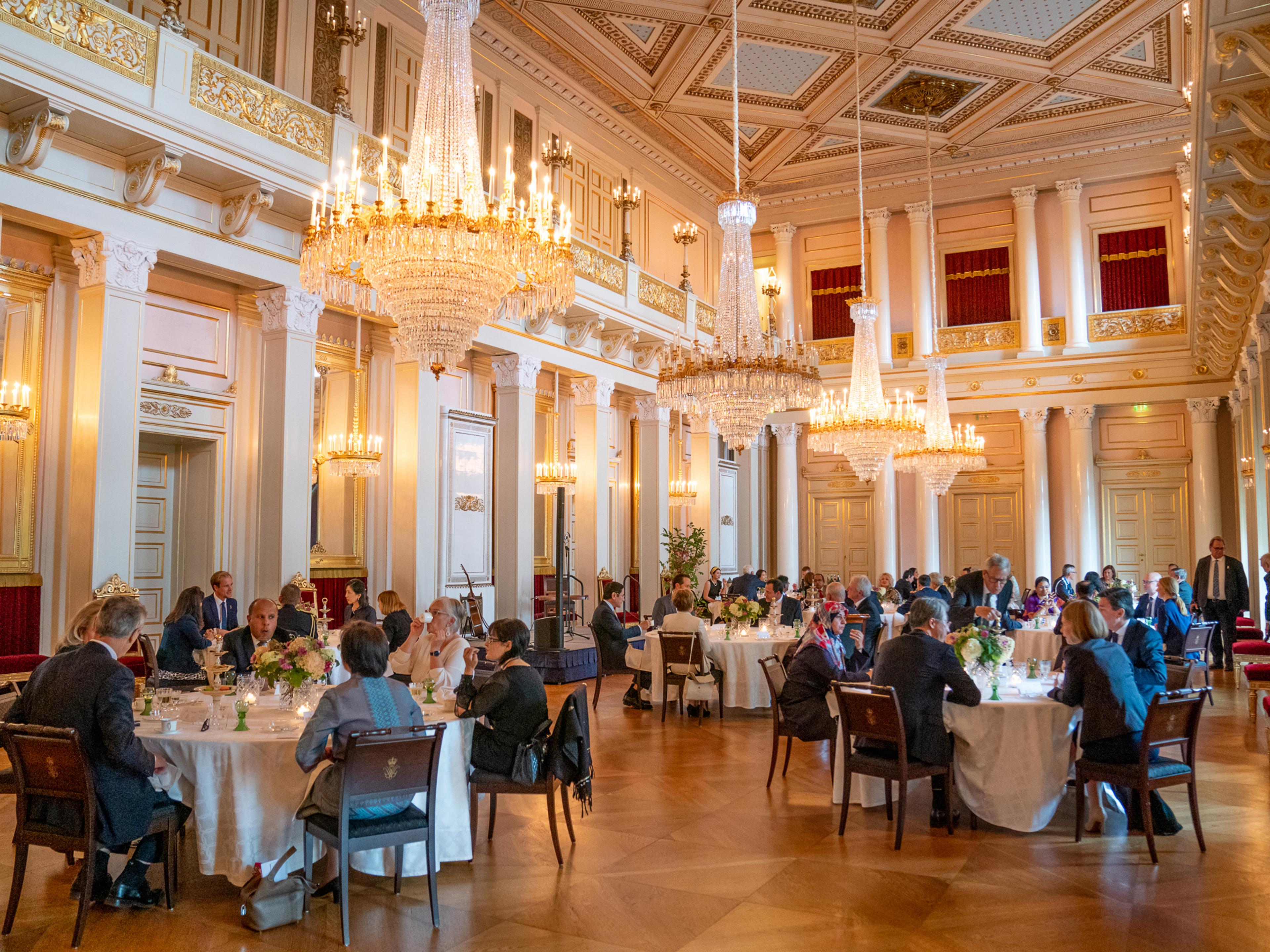 Gjester sitter ved en rekke runde bord plassert utover i Store festsal.