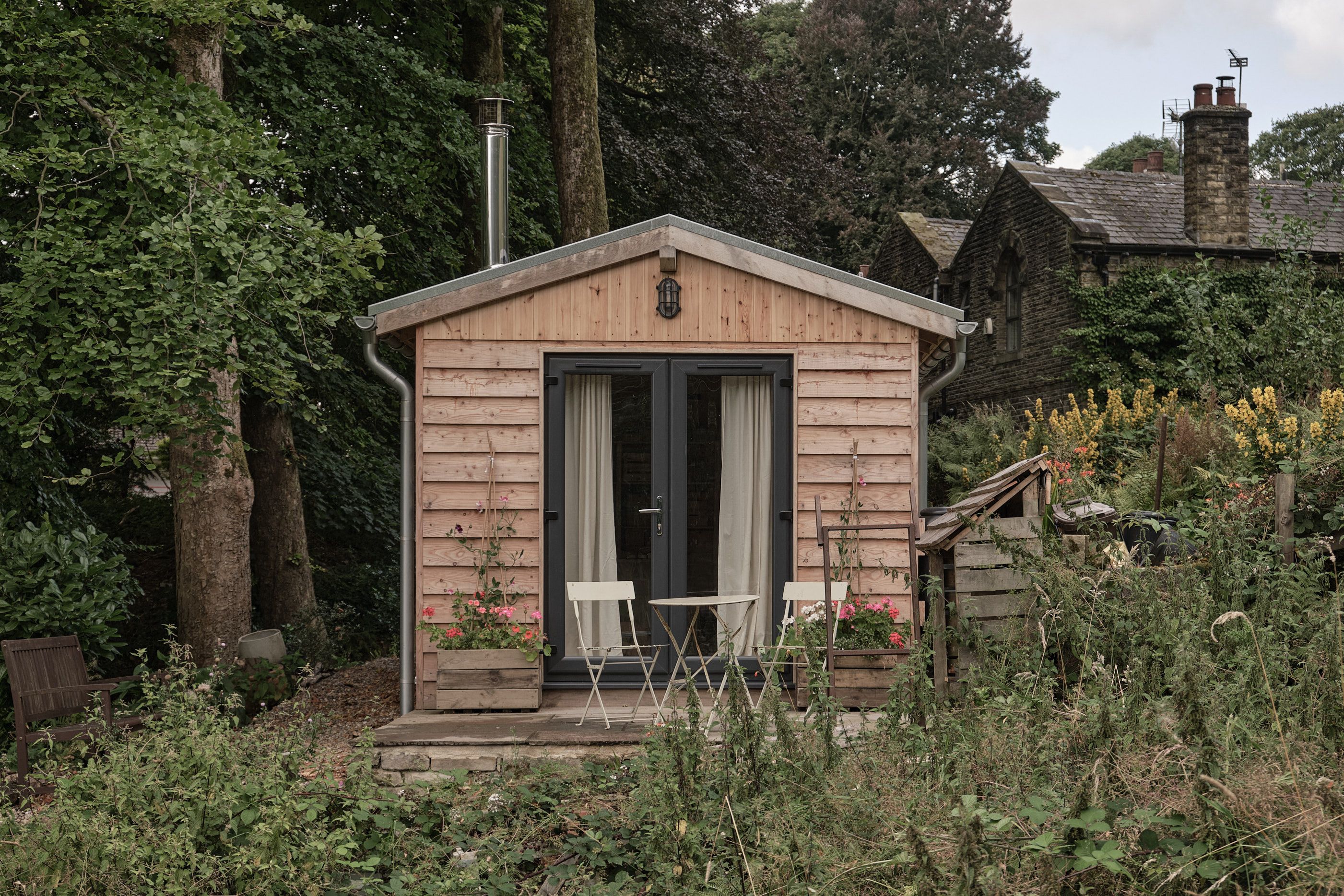 Exterior view of a bespoke garden studio built by our team, showing French doors and patio area