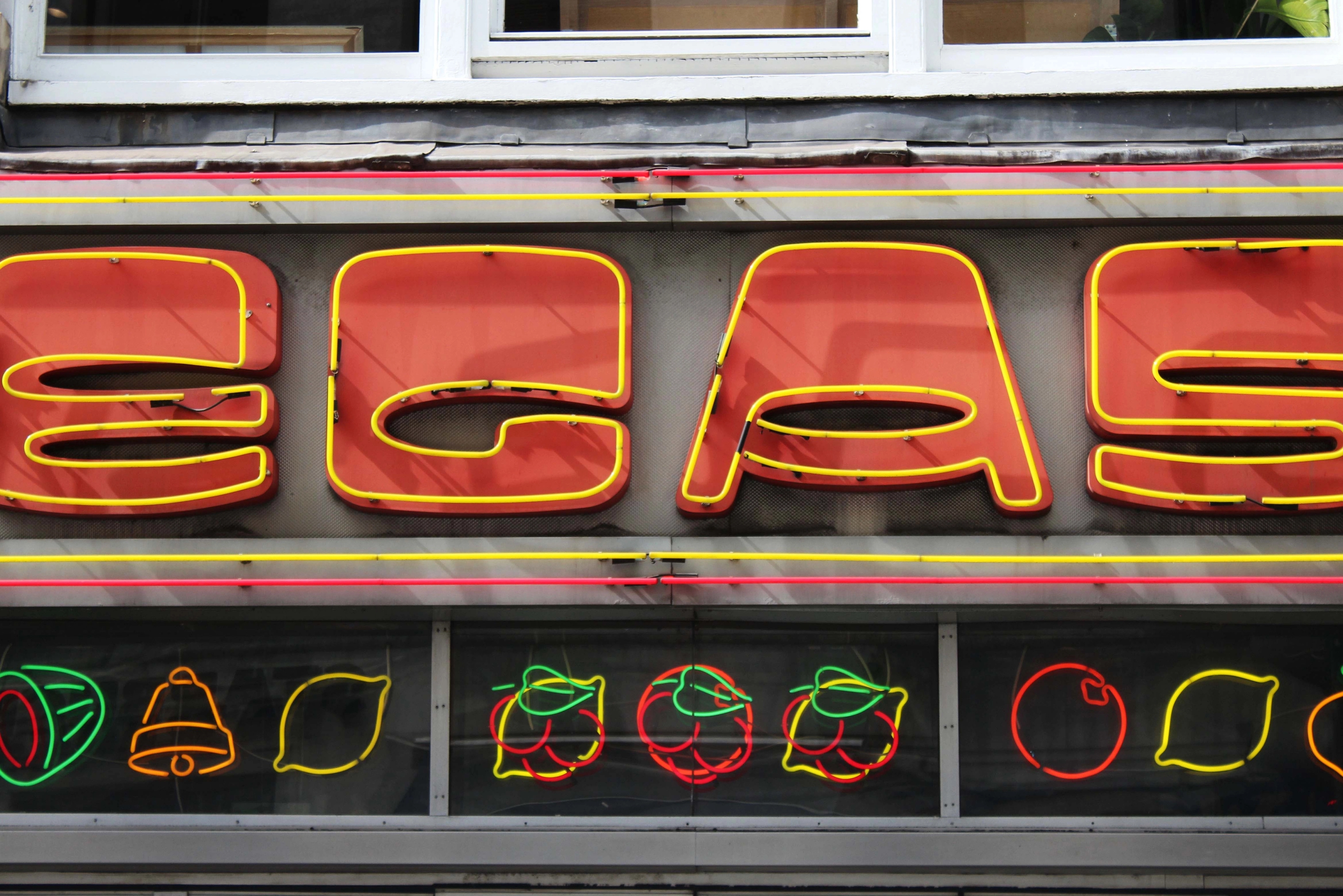 Close up of a neon sign reading "EGAS", with casino style fruit symbols below.