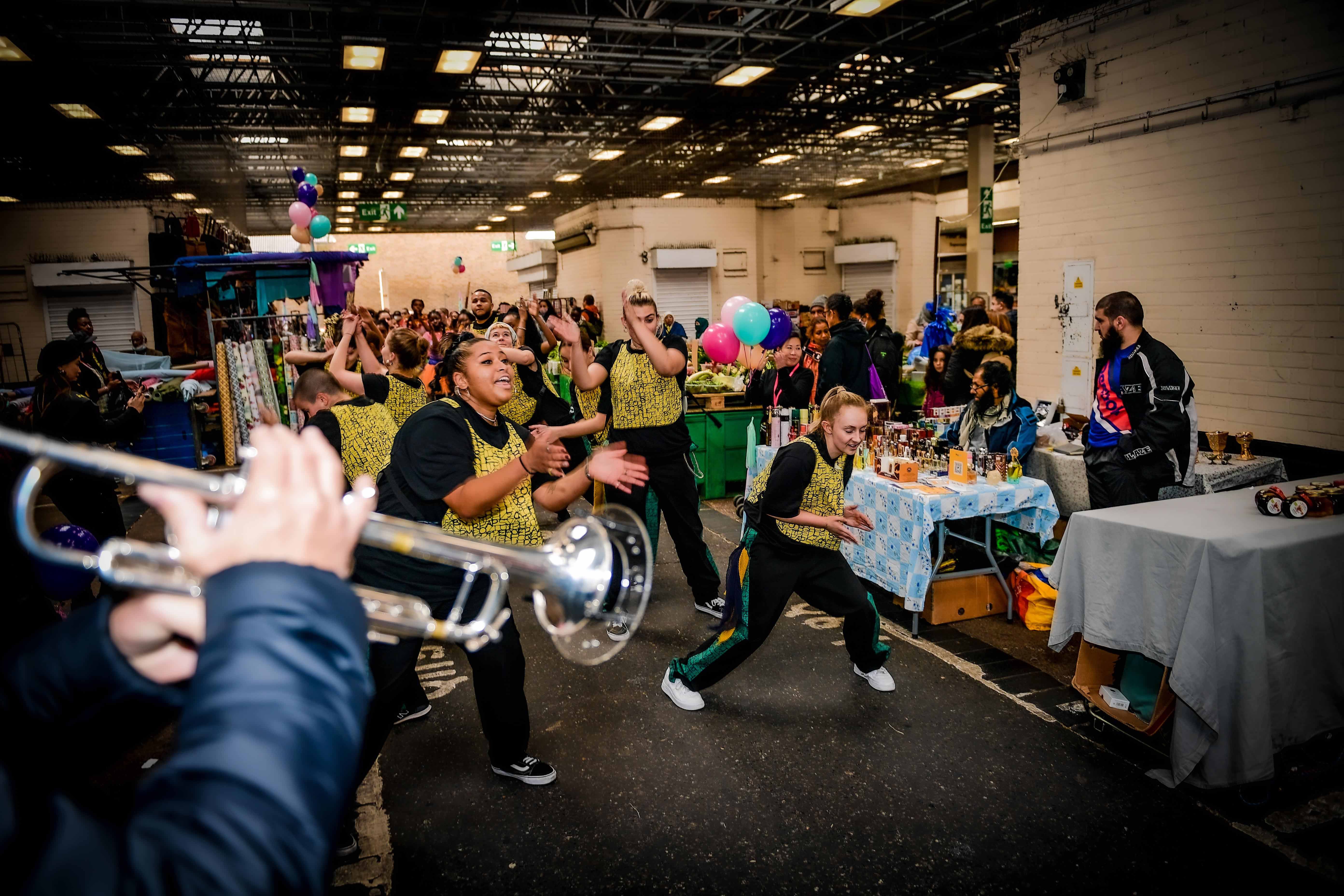Group of adolescents wearing yellow vests dancing and singing and some with instruments.