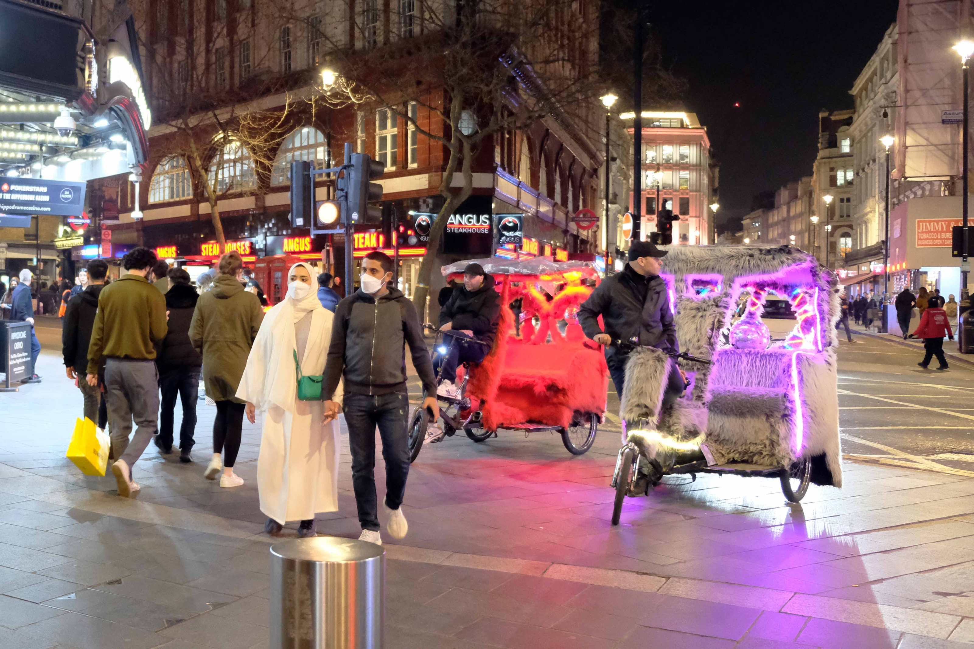 Two colourfully lit pedicabs in an open public space.