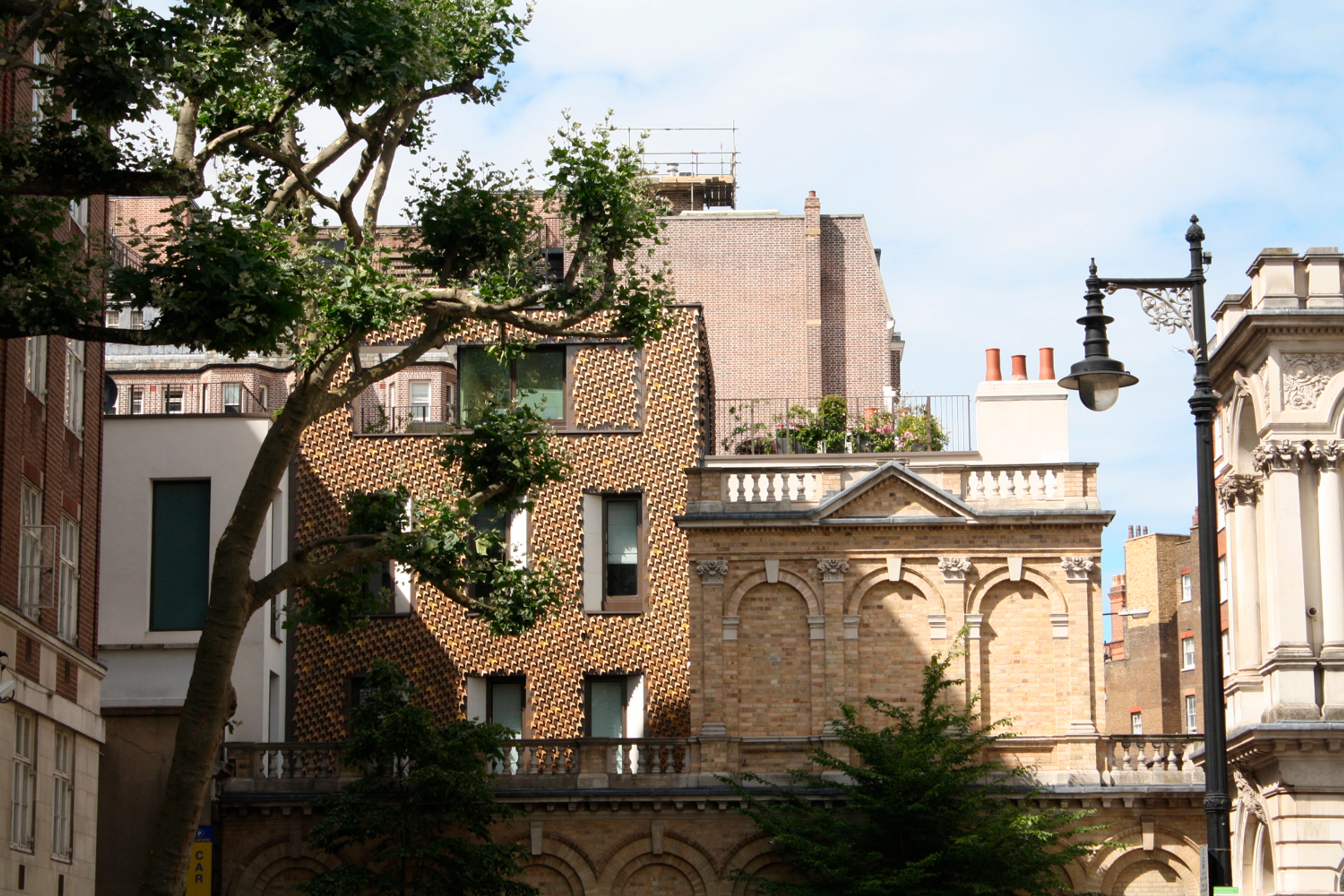 Roof and chimney details with a tree and light column.