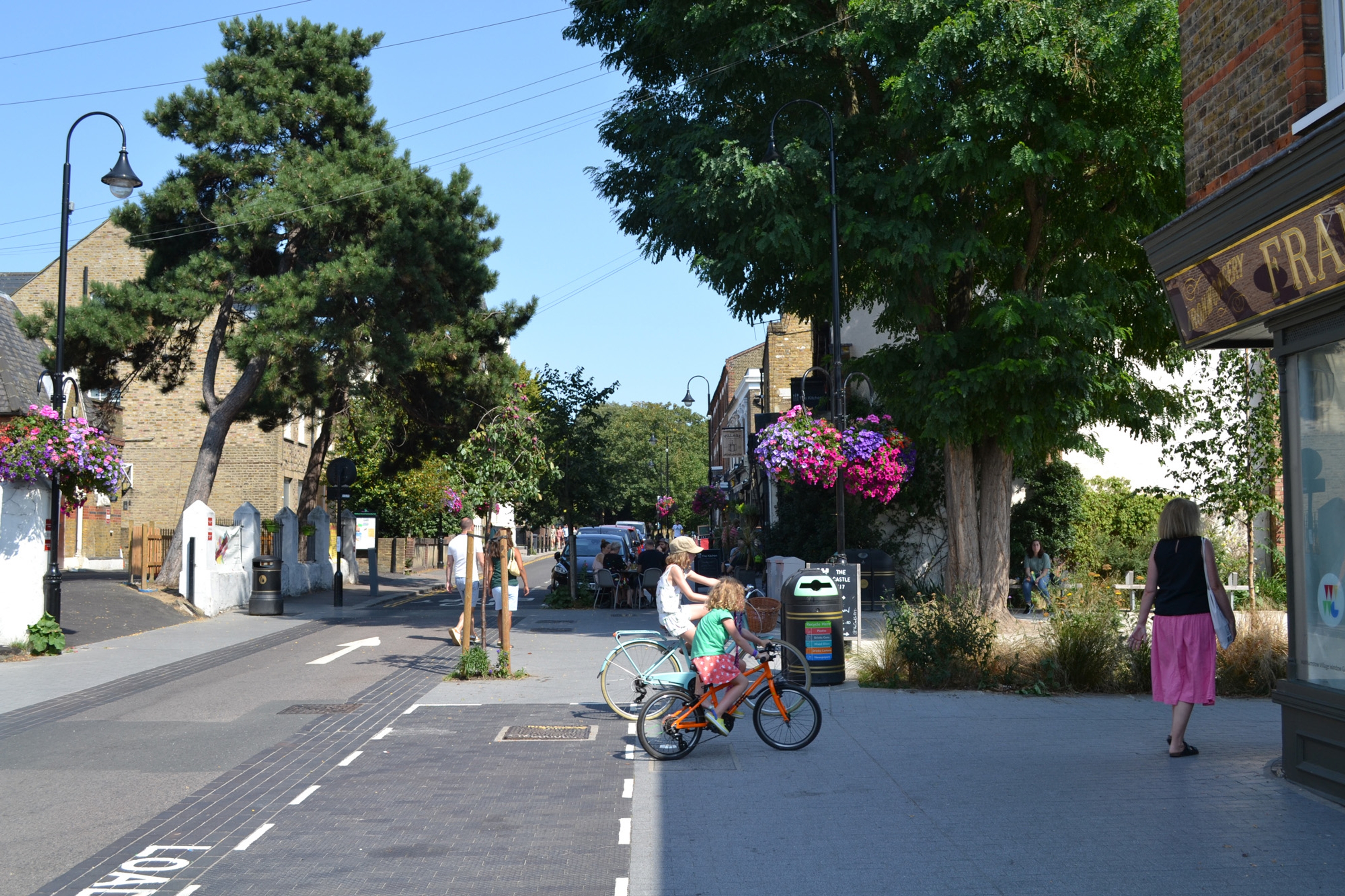 A street with a flush carriageway and children cycling.