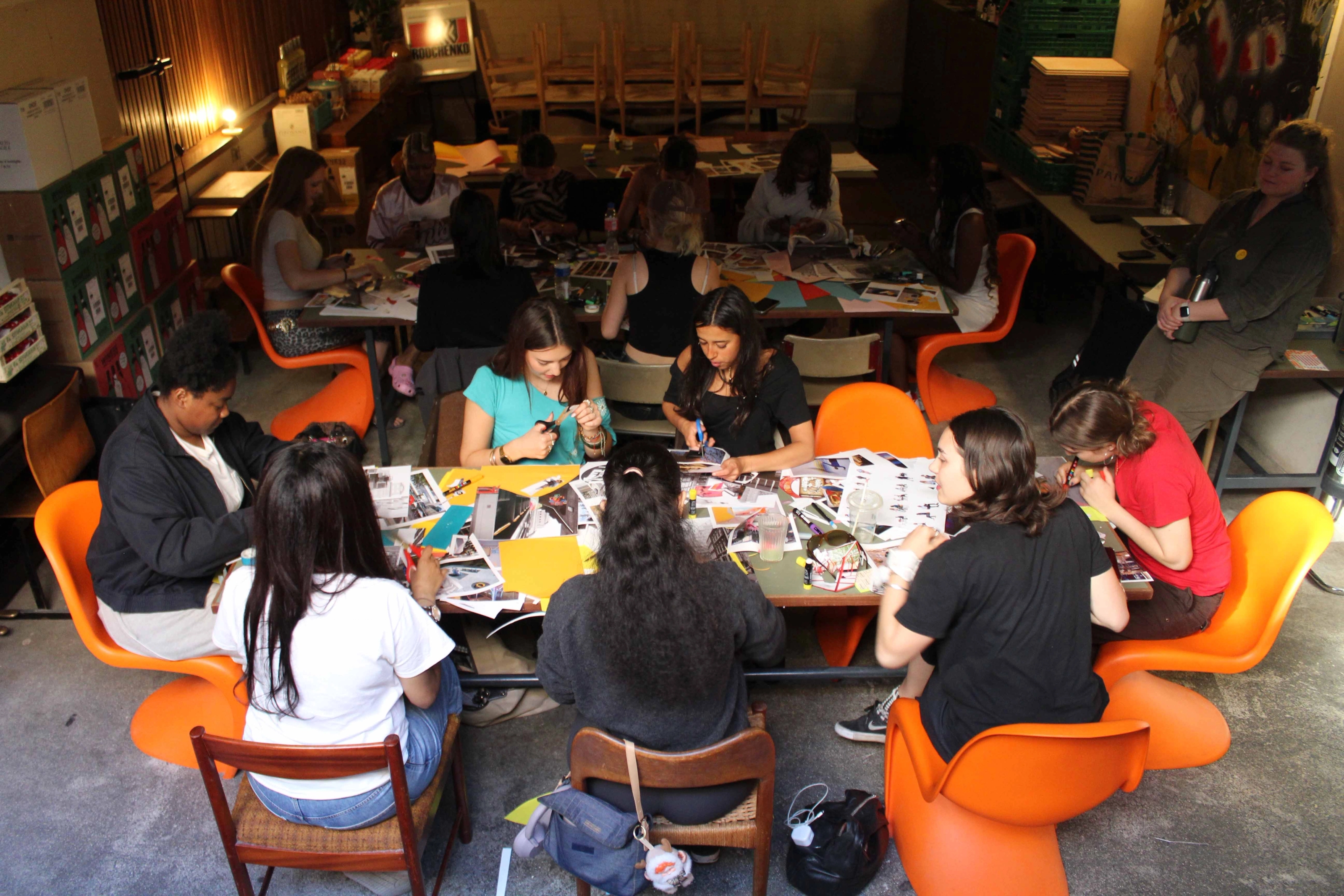 A group of people sitting around a table with collaging materials as they engage in a collaging exercise.