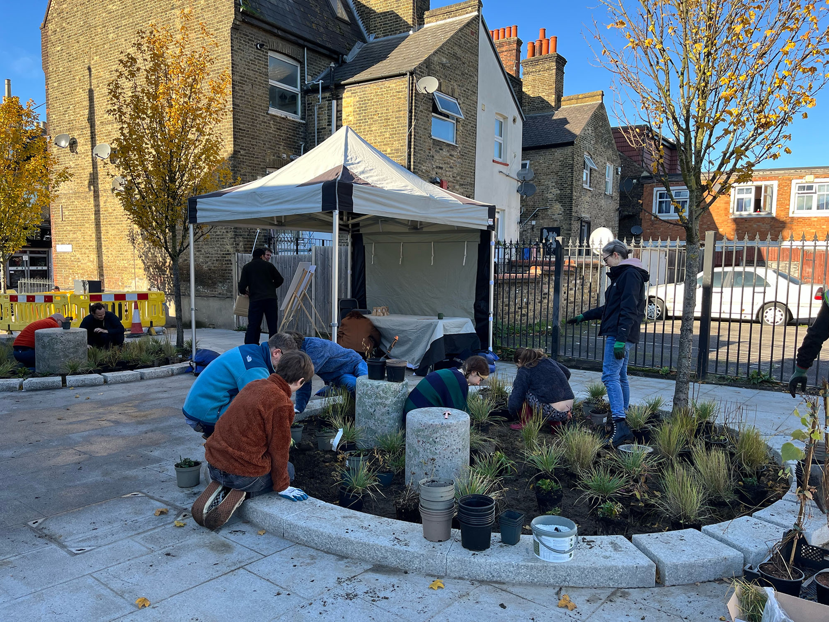 People kneeling around a planting bed working in the soil.