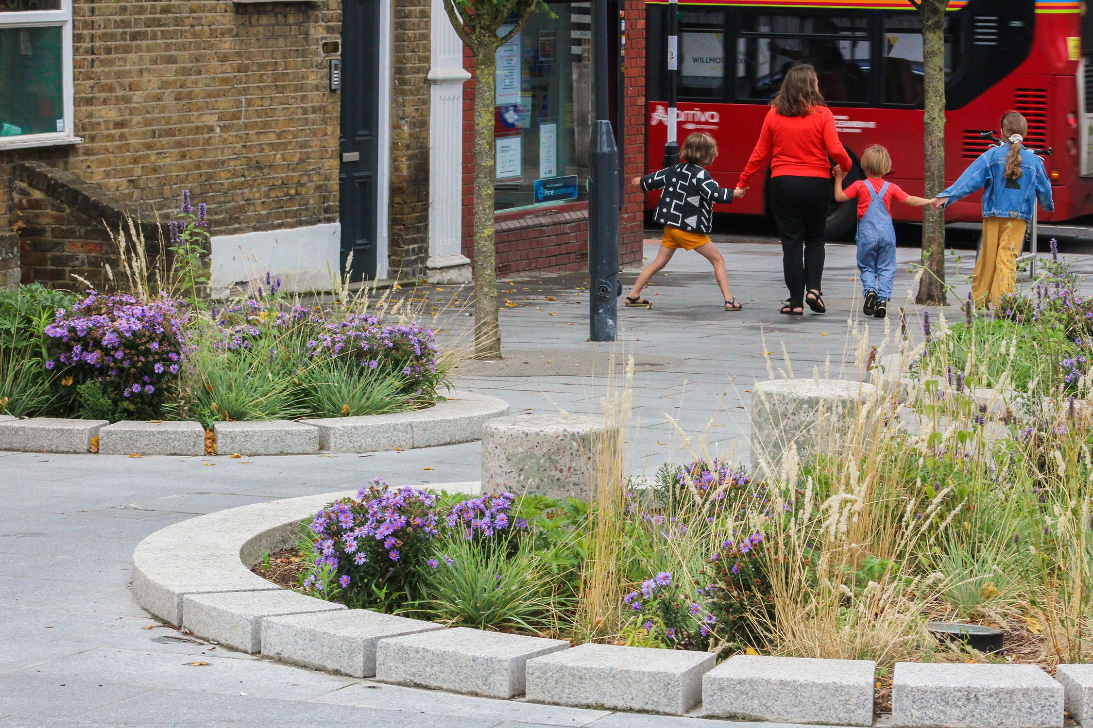 Two plant beds on a pavent with family walking hand in hand in the distance.