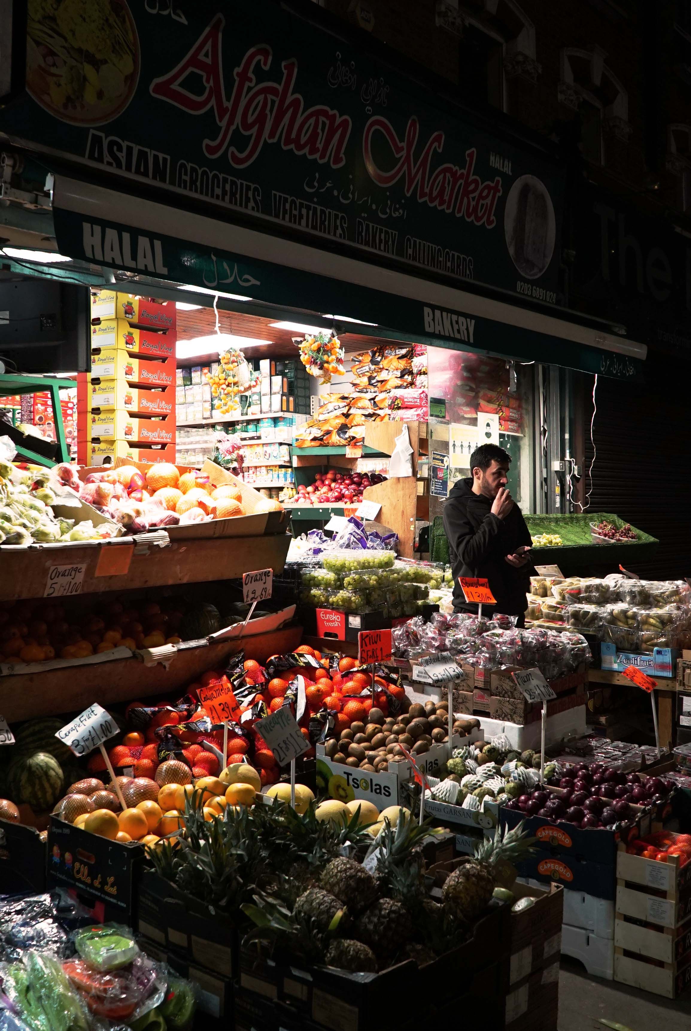 Photo of a grocery store at night with fruit and vegetable produce on display outside.