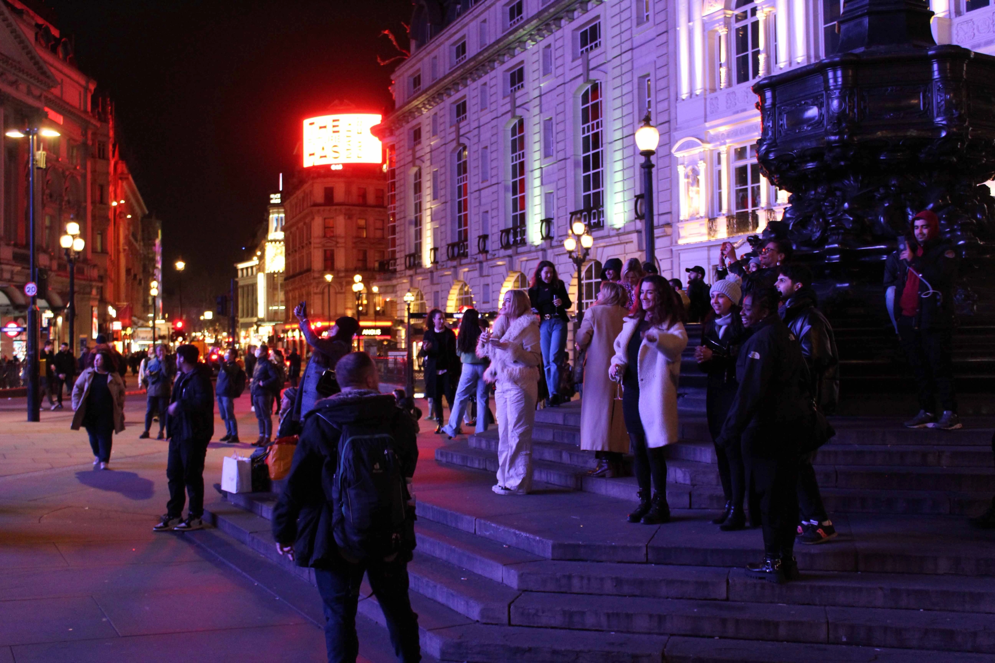 People standing on the steps of a monument at night.
