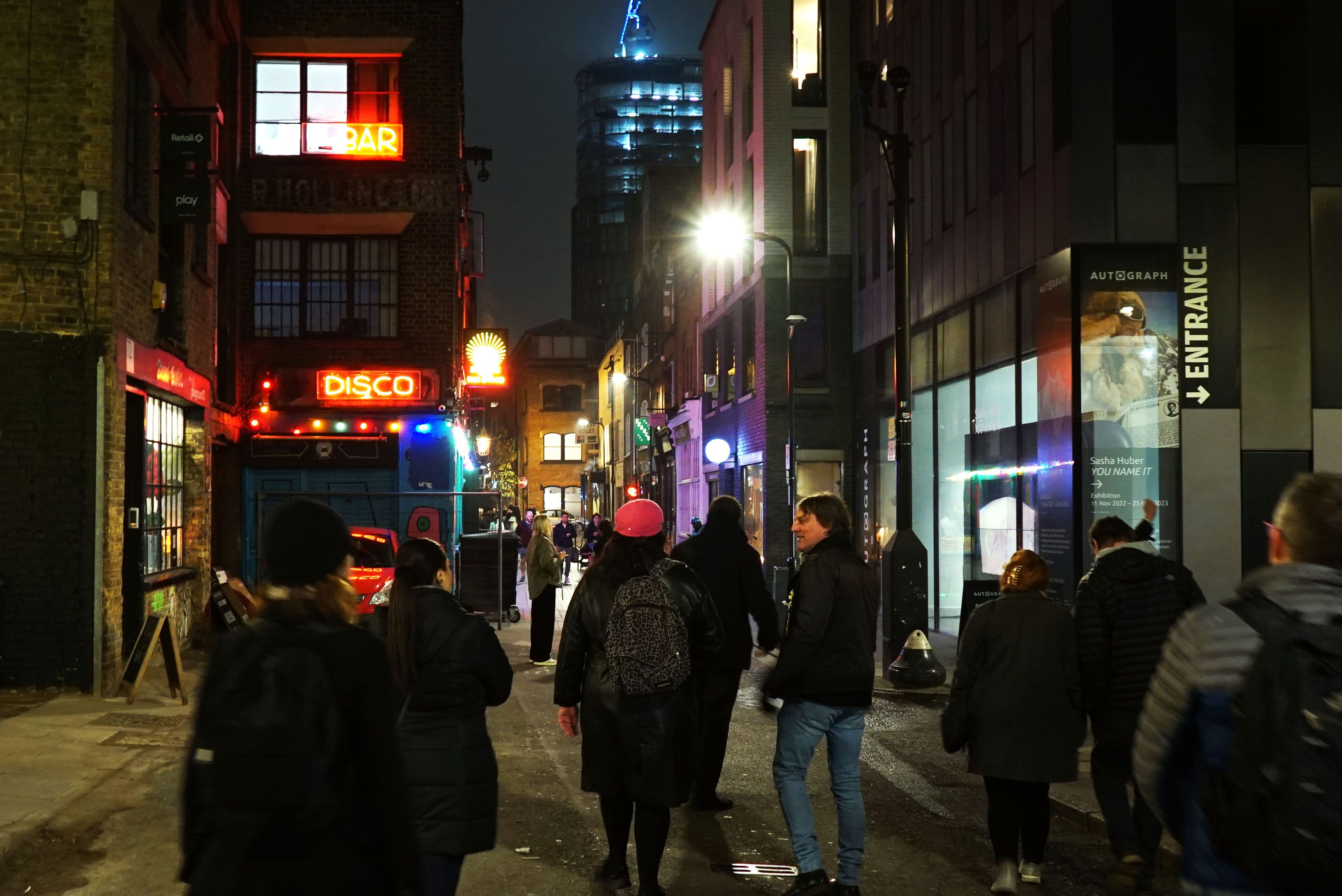 Photo of people walking down a dark street with litup shops and signage