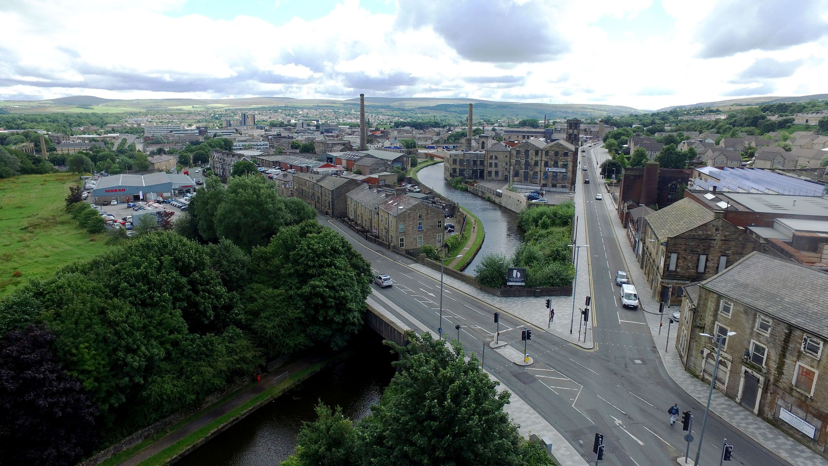 A photograph taken from above a quiet junction showing trees and some houses alongside.