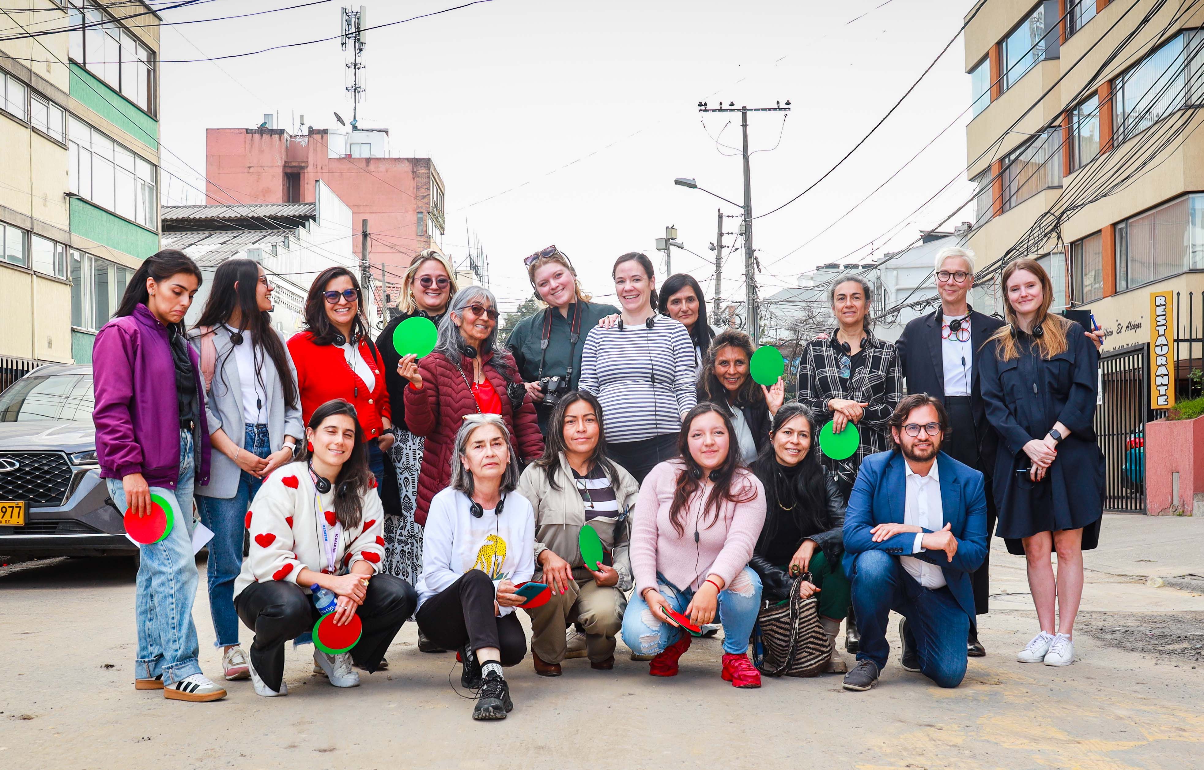 A group of people standing in the middle of a street in Bogotá holding green and red paper circles.