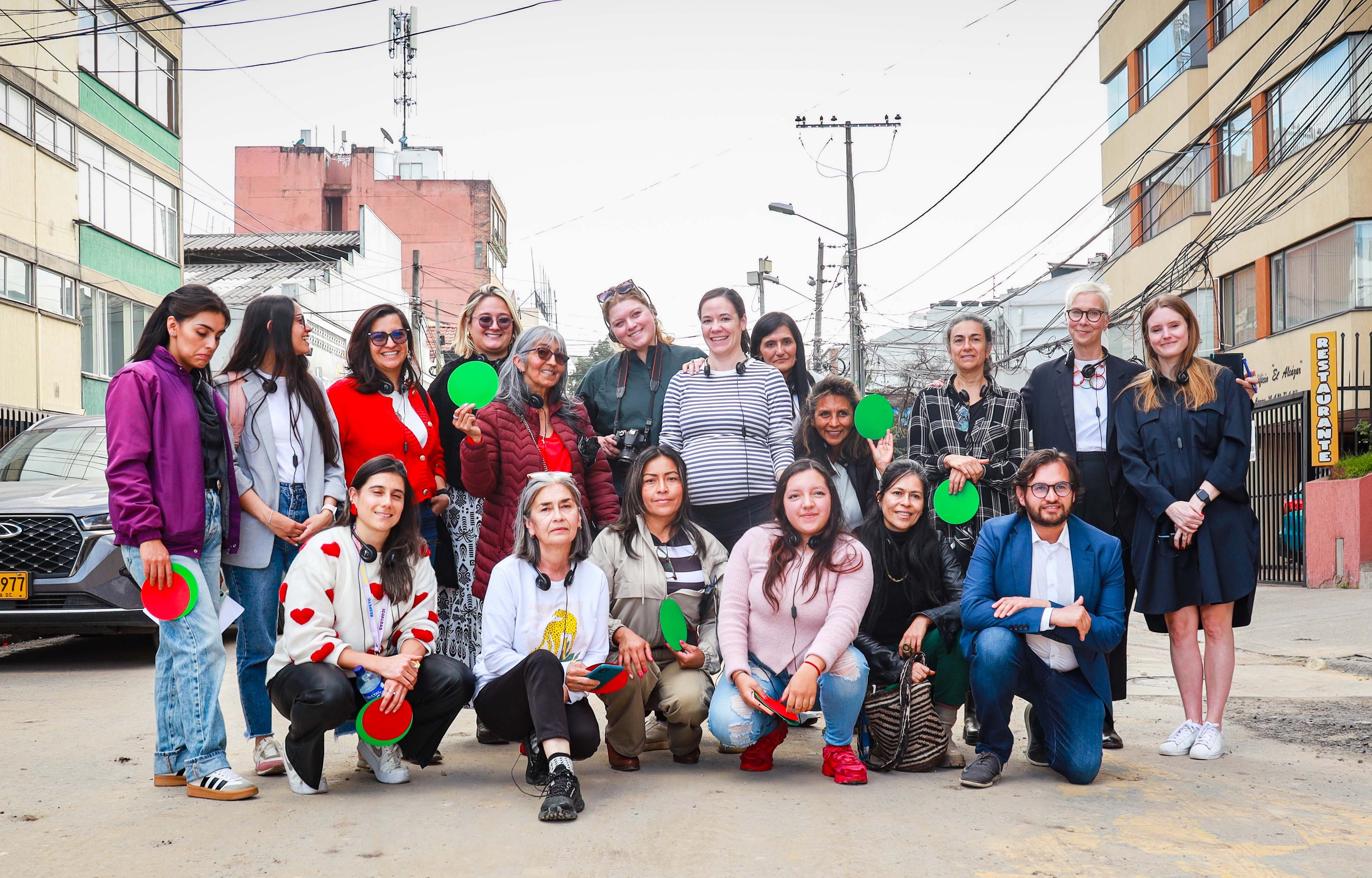 A group of people standing in the middle of a street in Bogotá holding green and red paper circles.