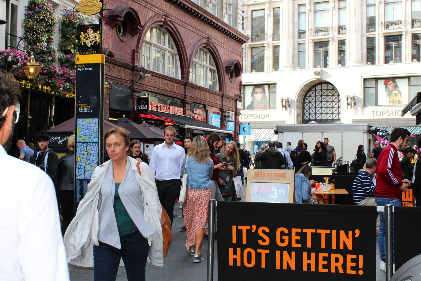 Crowded side street by Oxford Circus underground station.