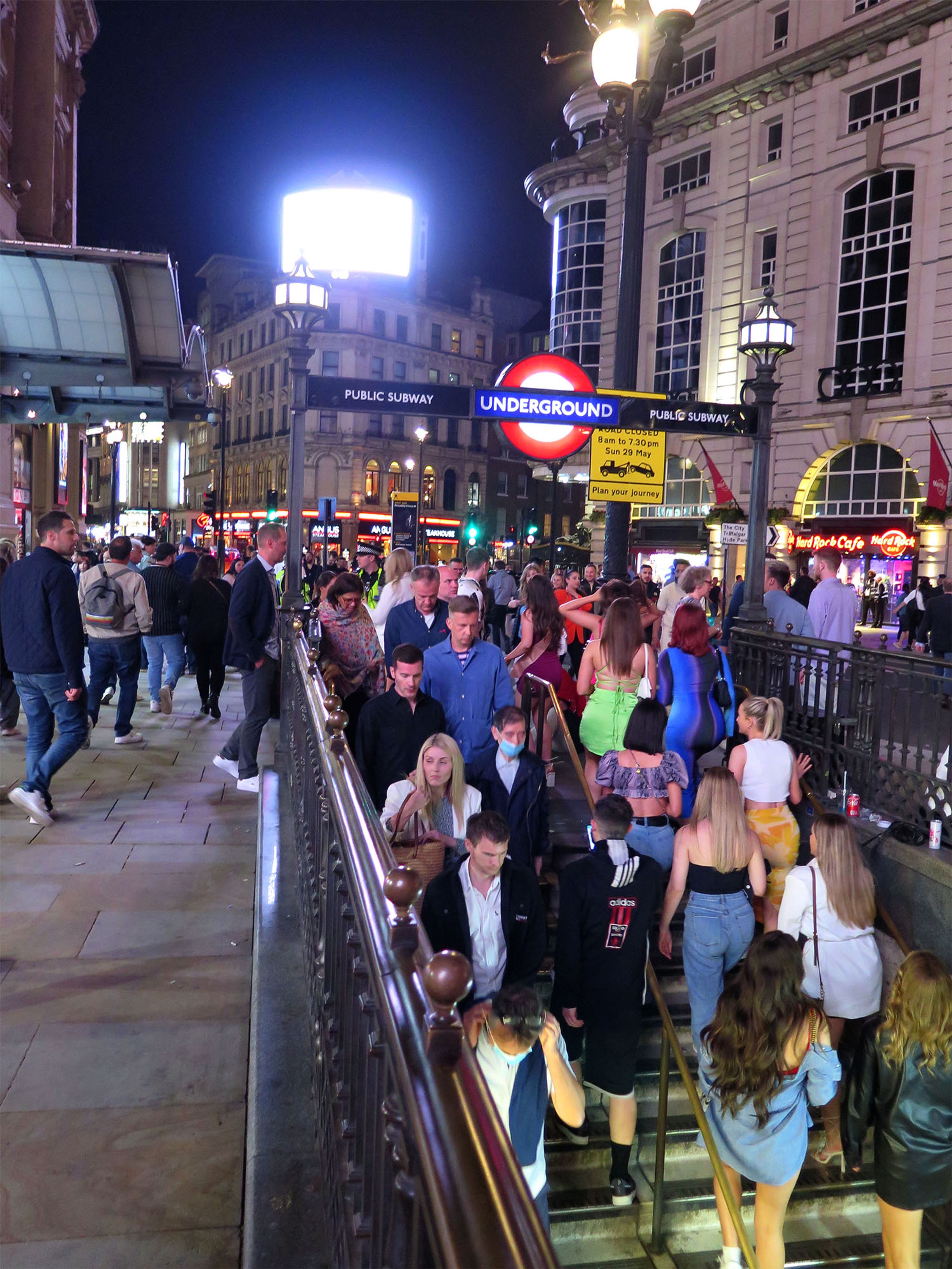 People walk up and down the stairs going into an underground station.