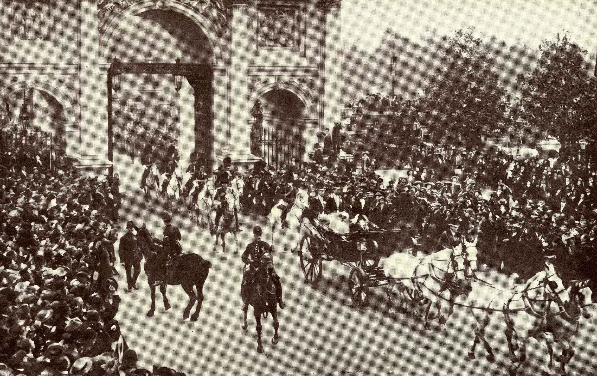 Historic photograph of a royal horse-drawn carriage passing through Marble Arch with spectators lining both sides of the street. 