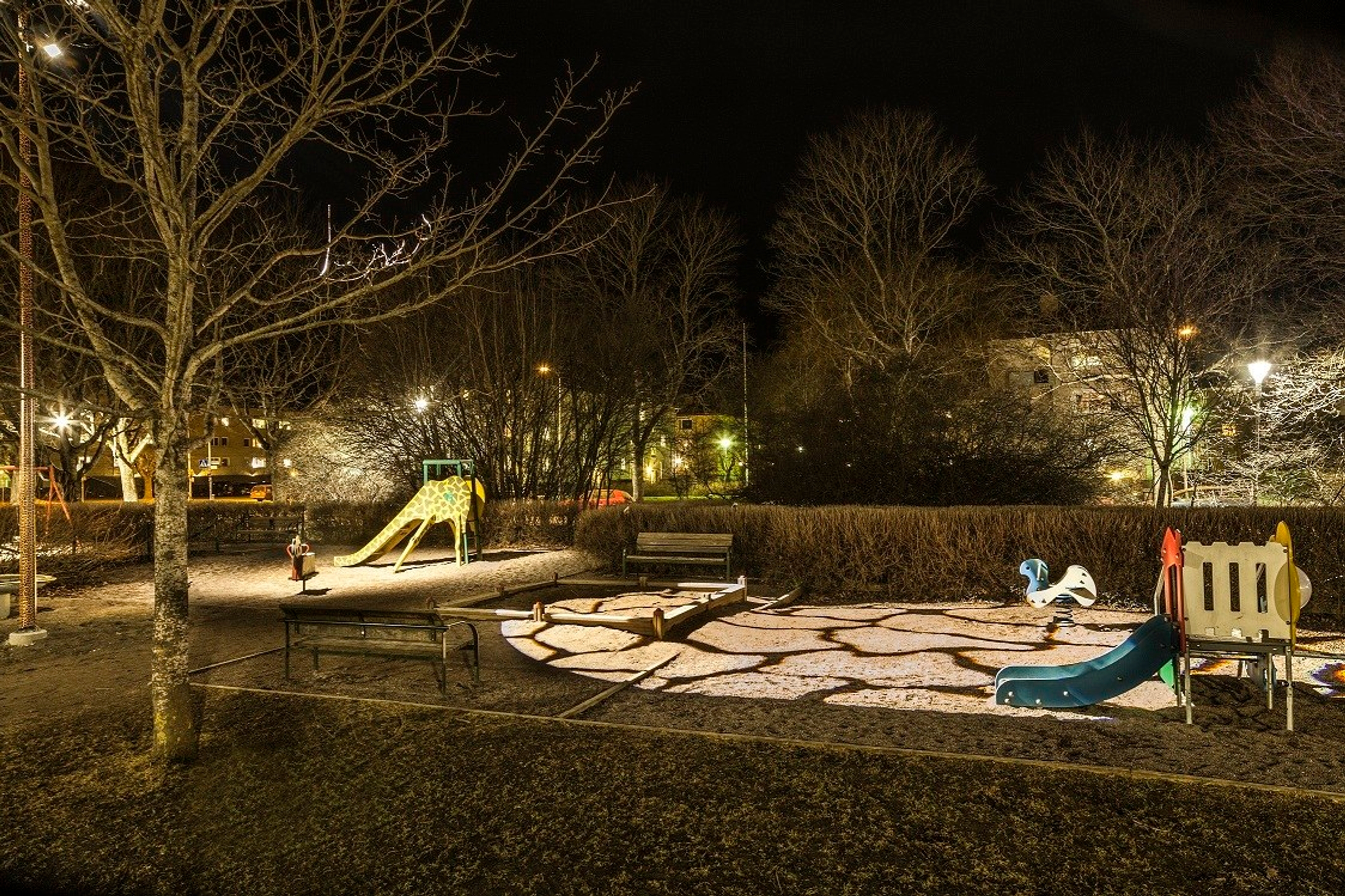 A playgound illuminated at night with light projected onto a slide.