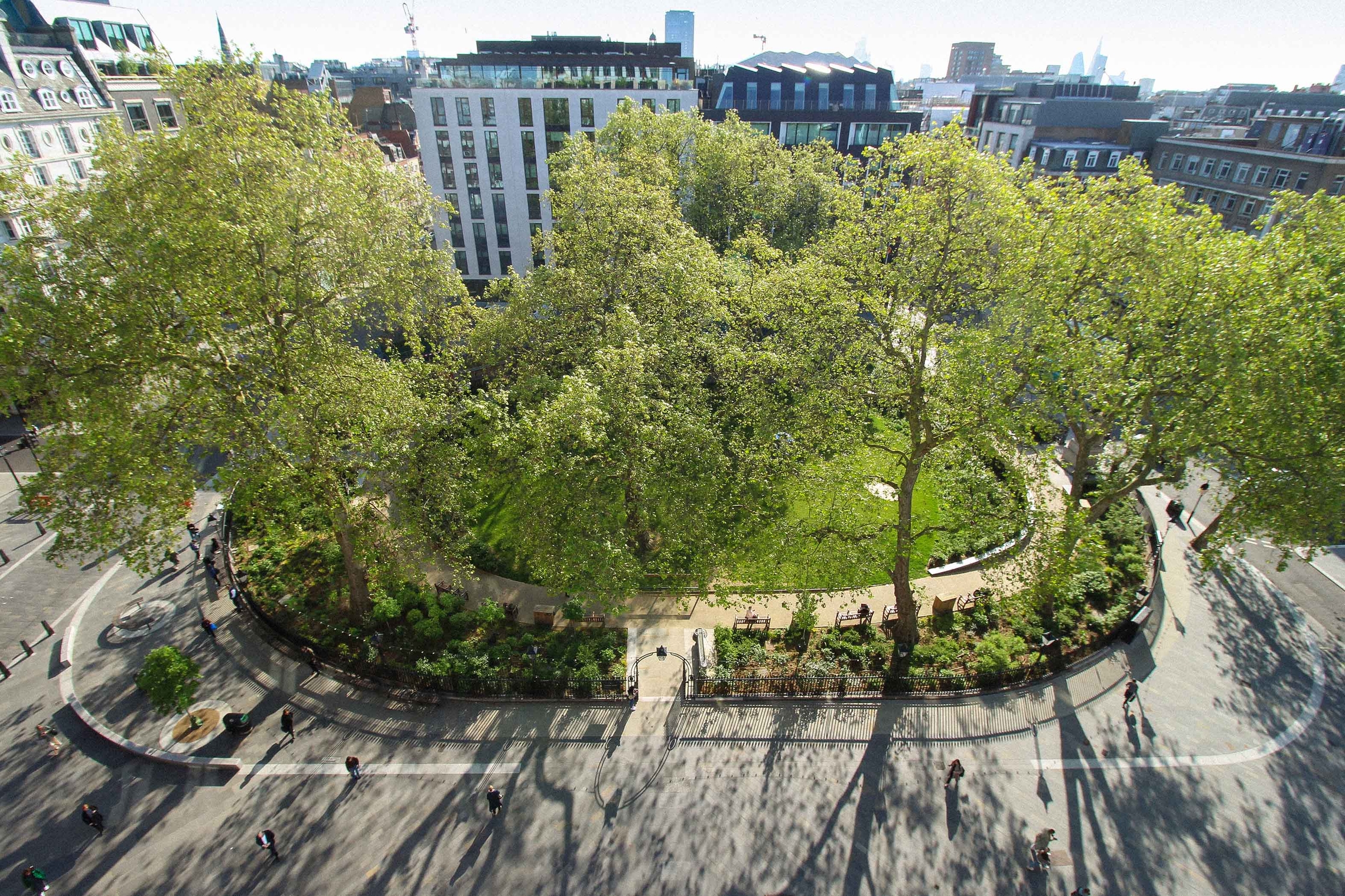 Photograph of Hanover Square from above, showing grassy space and trees with some tall buildings in the background.