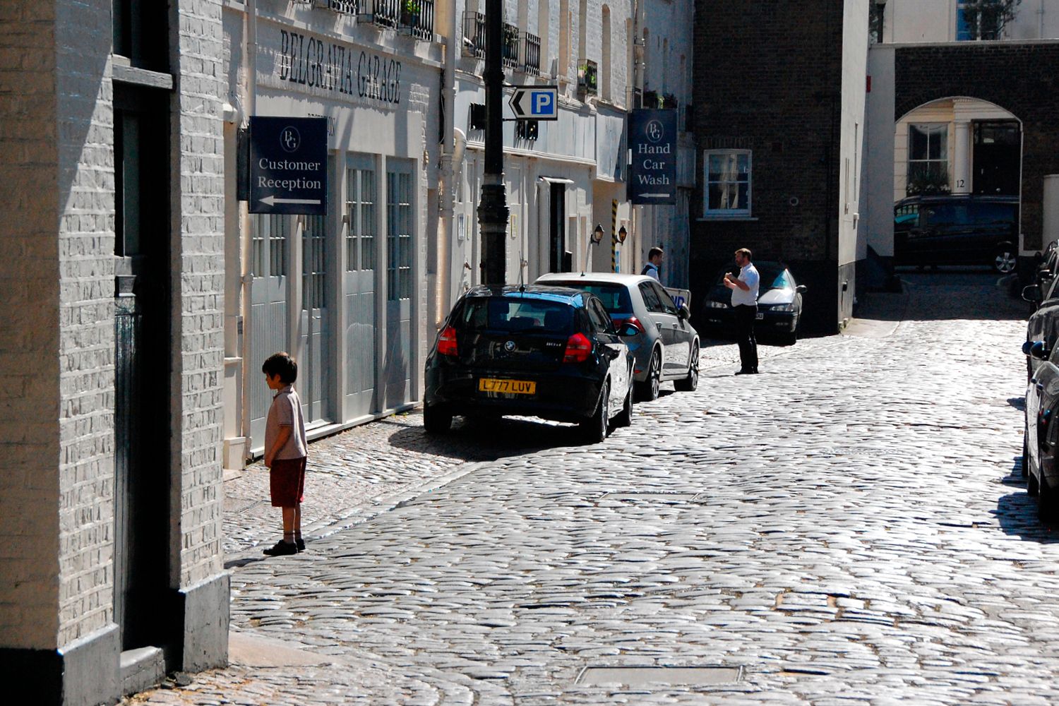 A child stands on a quiet cobblestoned street.