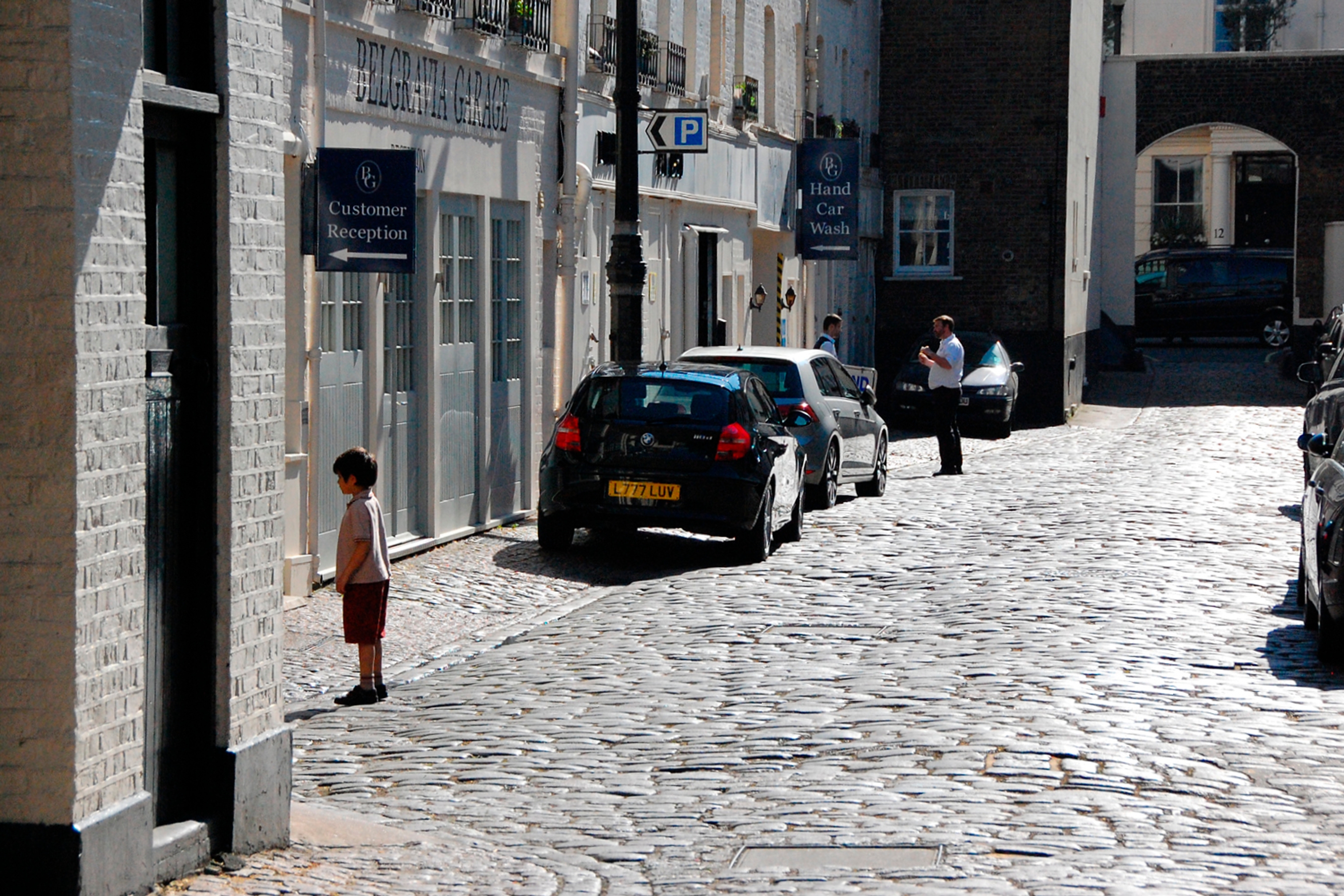A child stands on a quiet cobblestoned street.