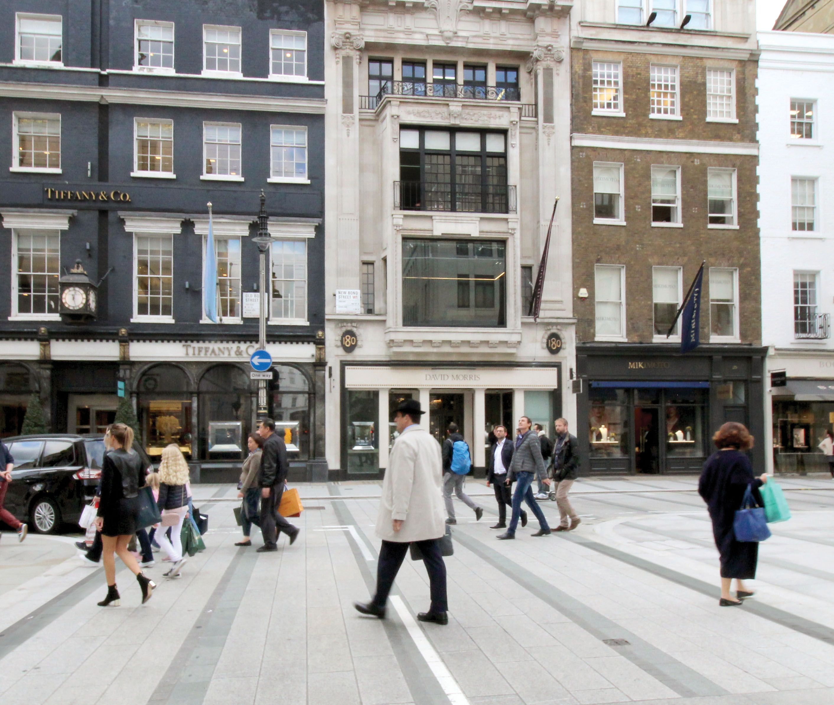 People walking on the pavement in front of a high street of shops