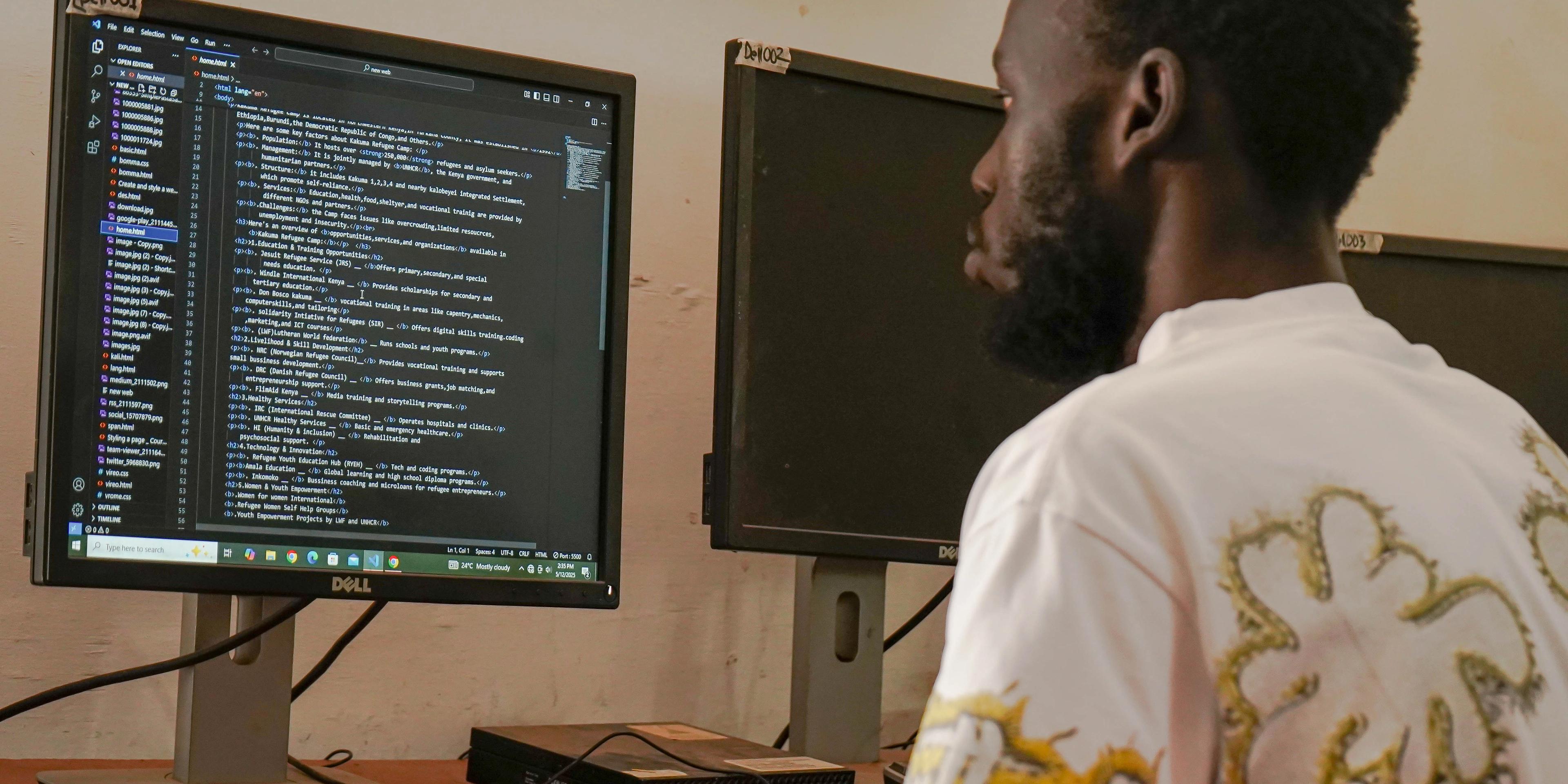 a man is sitting in front of a computer monitor .
