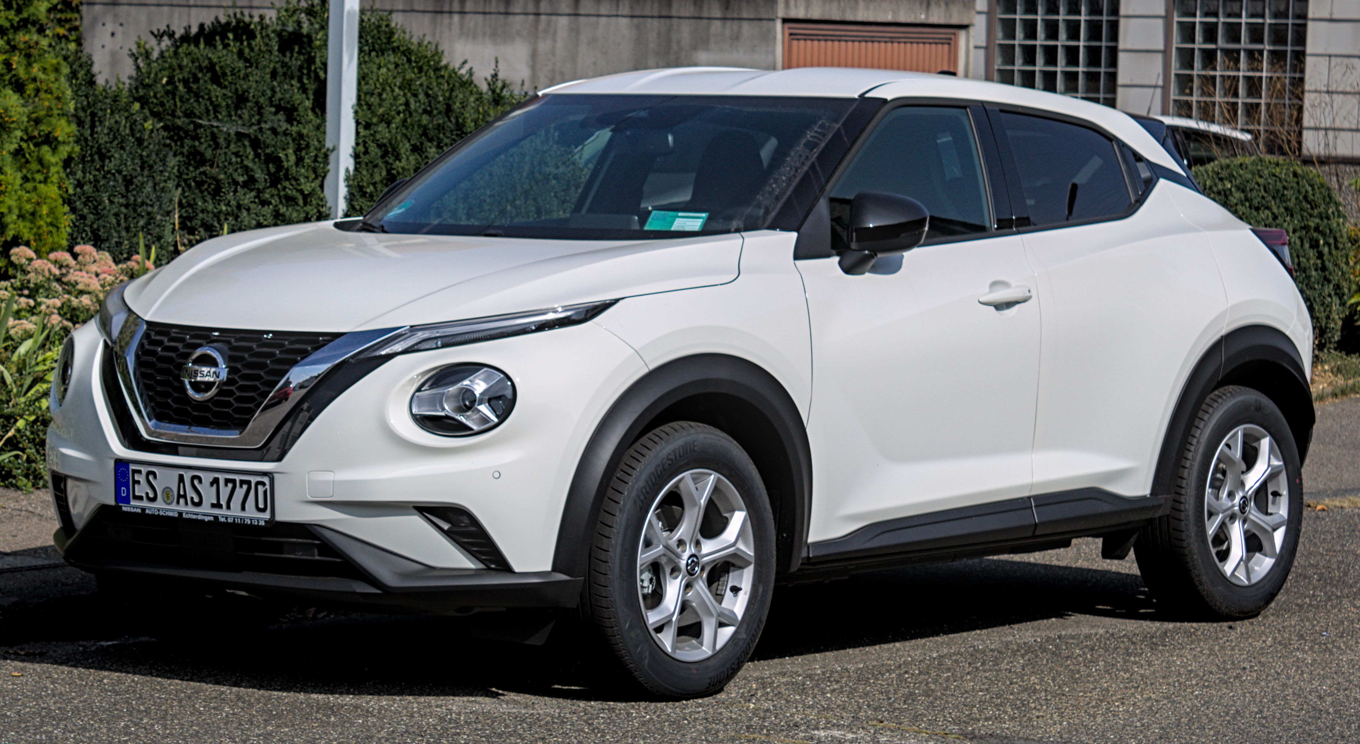A dynamic shot of a Nissan Juke driving on a city street. This compact crossover is powered by the highly efficient 1.3 DIG-T engine, co-developed with Renault.