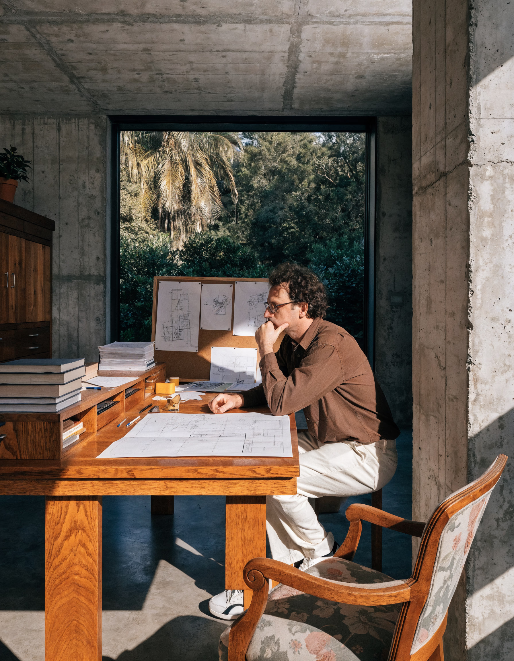 Lucas Vandenberg, Founding Principal of Southward Studios, looking thoughtfully over architectural plans in a concrete-walled studio.