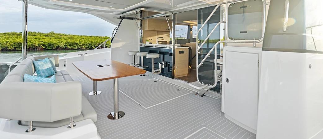 Aquila 50 Yacht aft cockpit with table and settee, opening to the galley