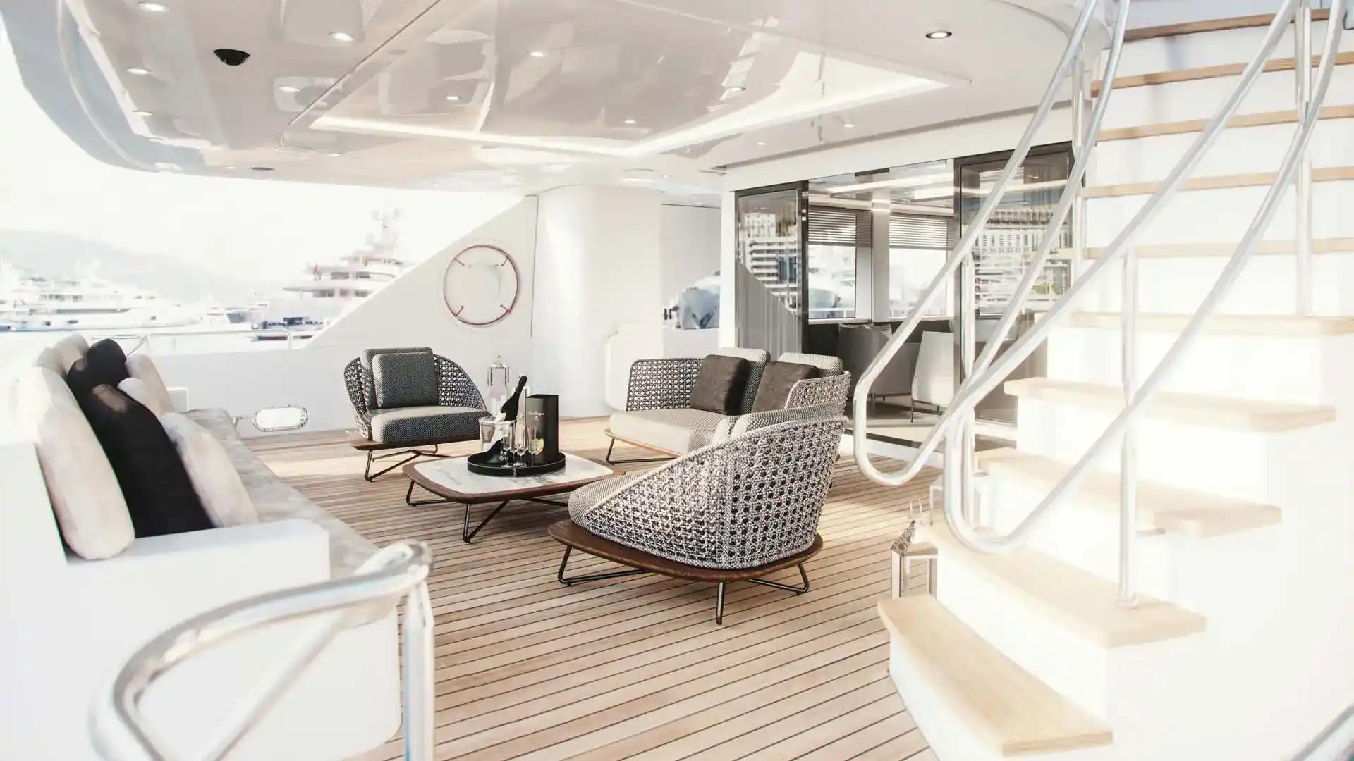 Westport 135 covered aft deck lounge with woven armchairs and stairway