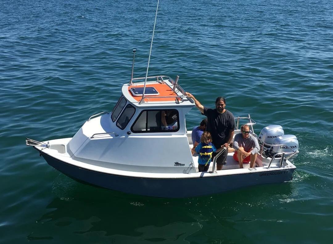 Family aboard a Greenough 17 pilothouse with twin Honda outboards on blue water