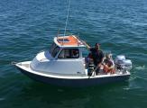 Family aboard a Greenough 17 pilothouse with twin Honda outboards on blue water