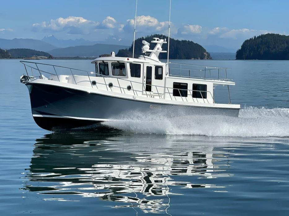 American Tug 395 with navy hull running at speed past wooded islands