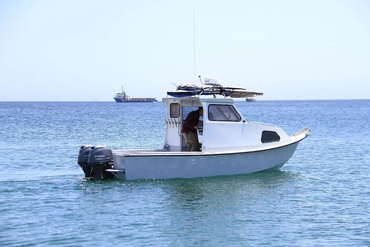 White Greenough 21 pilothouse with twin Yamaha outboards, side profile on open water